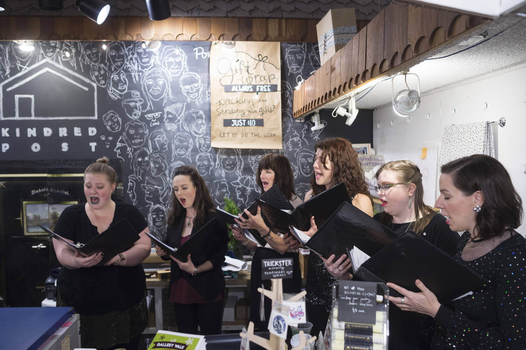 Members of “Bell Bell Bell, What Do We Have Here” sing carols at Kindred Post during Gallery Walk on Friday, Dec. 7, 2018. (Michael Penn | Juneau Empire)