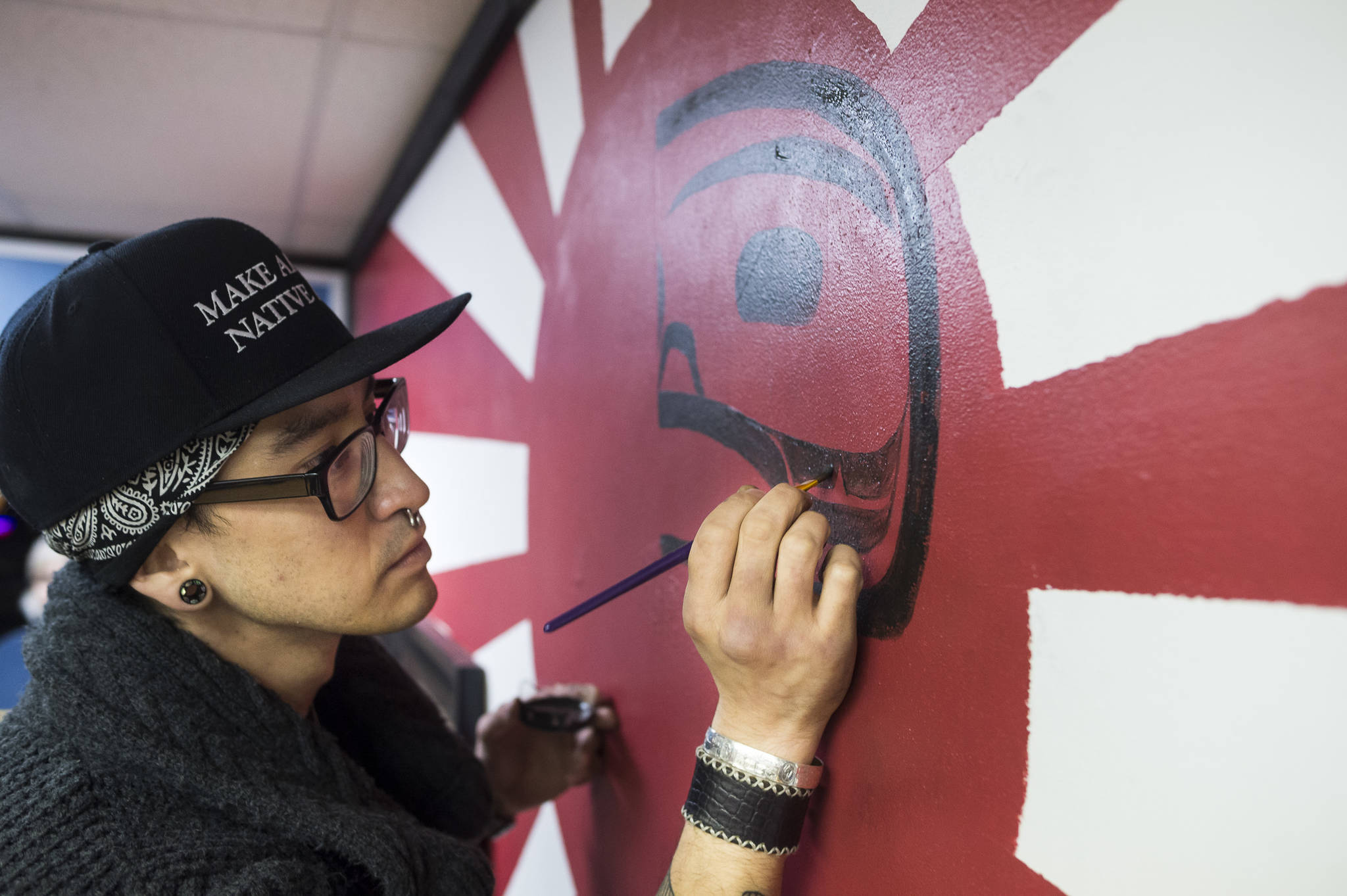 Artist Shane Brown paints the wall in 4th Coast Outfitters during Gallery Walk on Friday, Dec. 7, 2018. (Michael Penn | Juneau Empire)