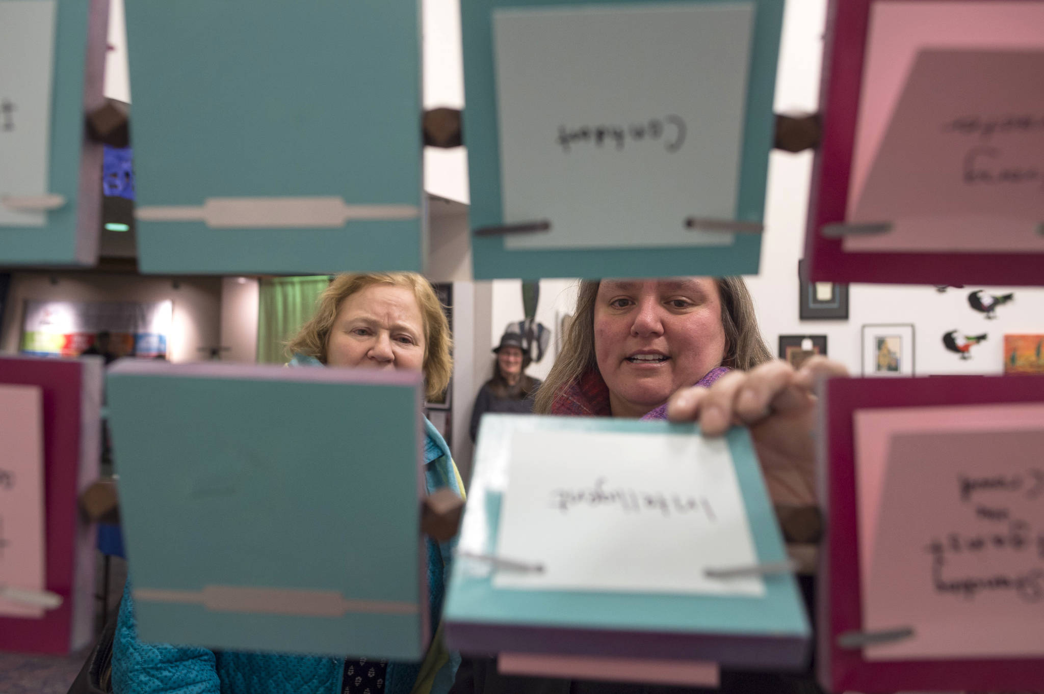 Cathy Needham, right, and Barb Sheinberg check out the “The Rolodex Project//On Leadership” by artist Sarah Campen, an interactive film and sculpture on display at The Davis Gallery in Centennial Hall during Gallery Walk on Friday, Dec. 7, 2018. (Michael Penn | Juneau Empire)
