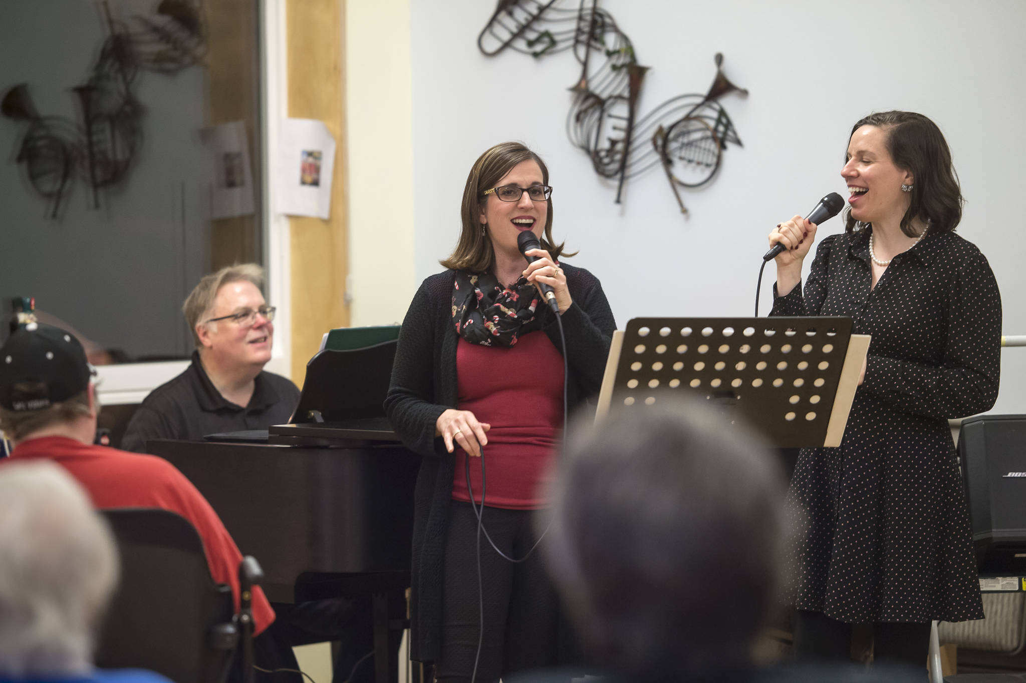 Heather Mitchell, center, and Allison Holtkamp are accompanied by Tom Locher on piano as they perform their Juneau Cabaret songs to seniors at Wildflower Court on Wednesday, Dec. 12, 2018.
