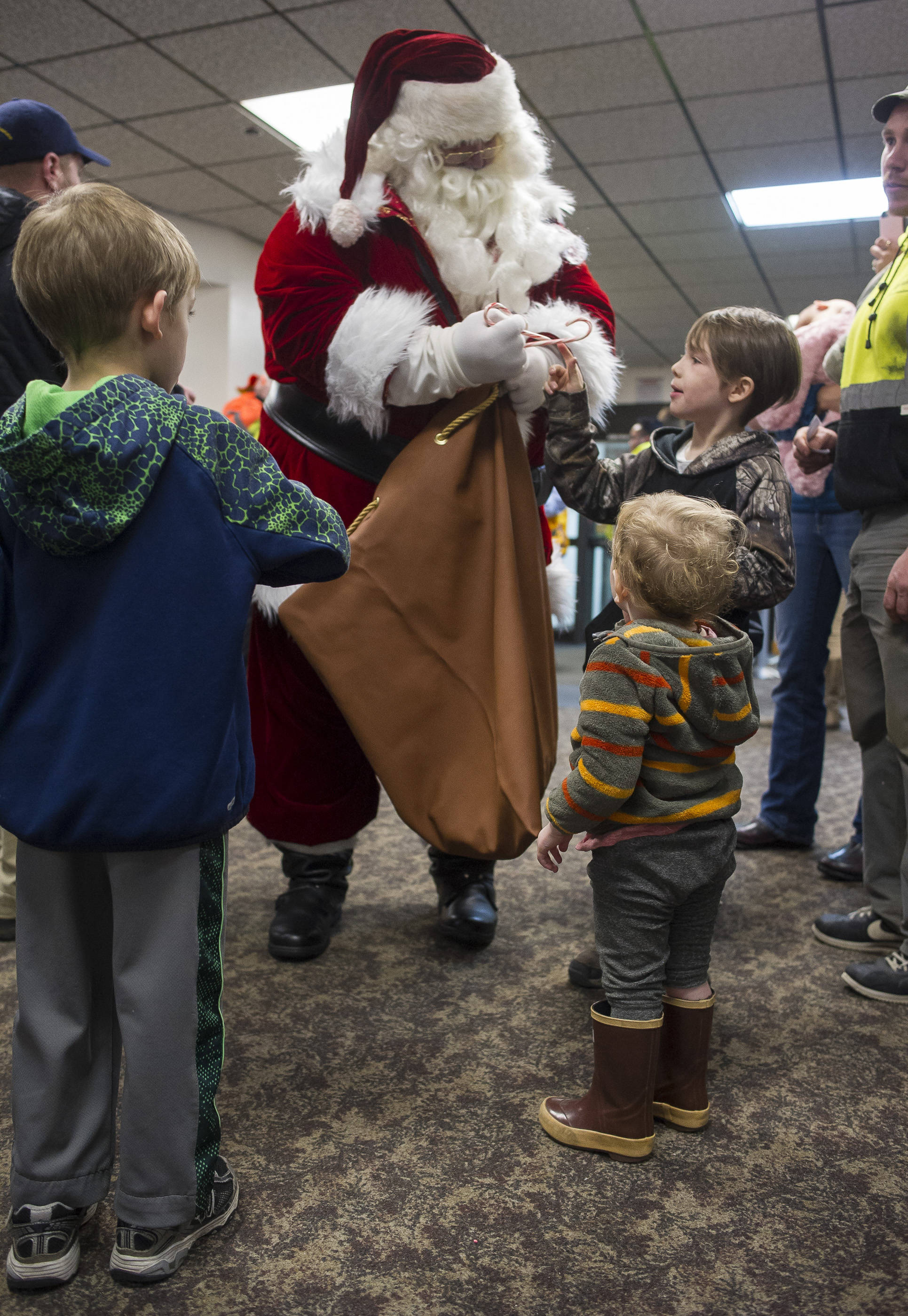 Santa gives out candy canes to children waiting in line for the annual Christmas Lights Flights at the Juneau International Airport on Friday, Dec. 15, 2017. Mendenhall Flying Lions put on the event, which is a fundraiser for the American Children’s Tumor Foundation. Petro Marine Services and Coastal Fuel also support the event. (Michael Penn | Juneau Empire File)