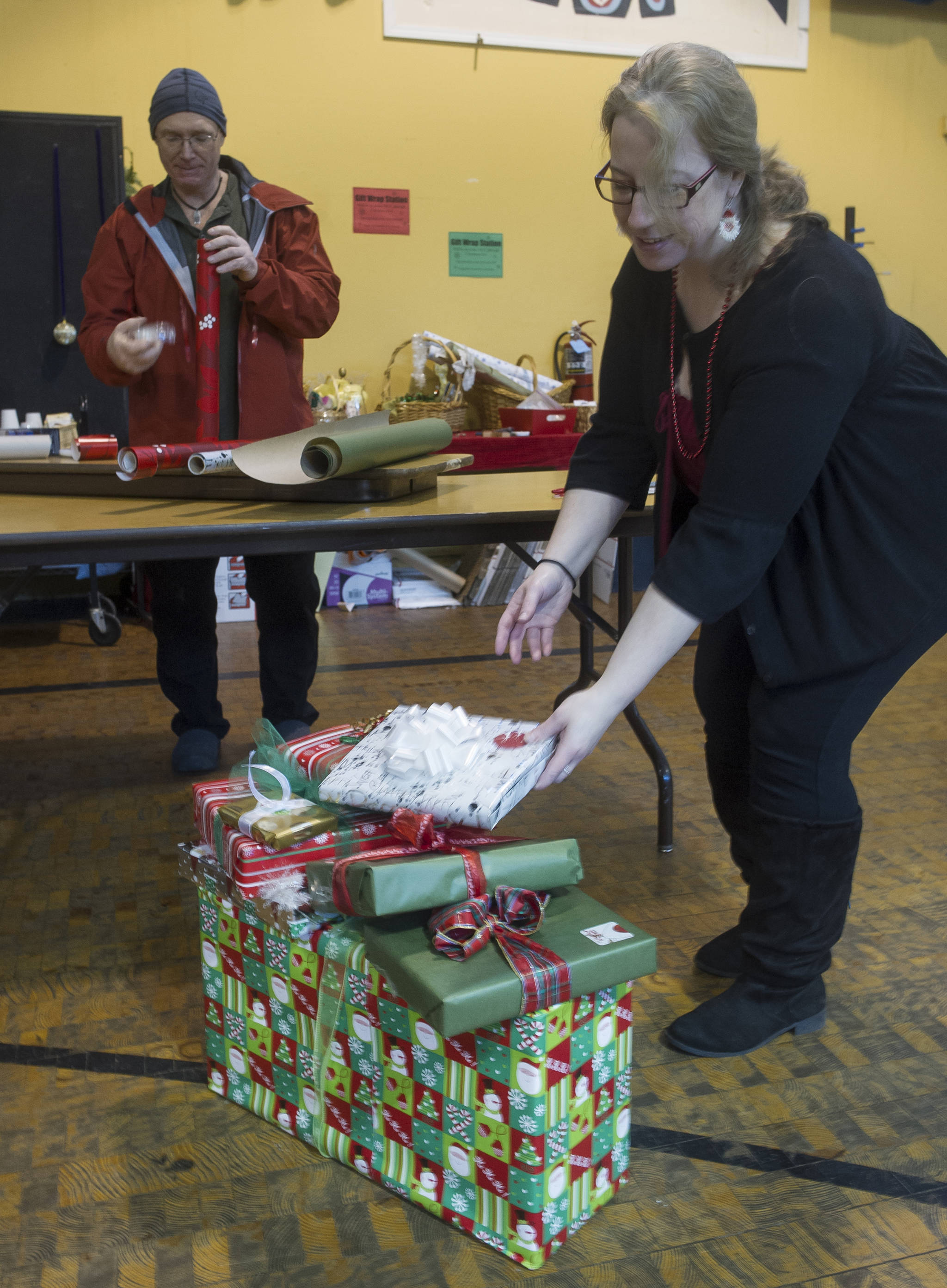 Jenny Rodriguez, right, and Gene Laughlin make use of the Christmas wrapping station at the Juneau Arts and Culture Center to finish off their gifts. For a donation people can find wrapping paper and all the trimmings. The JACC will be open every day and until 3 p.m. on Sunday, Christmas Eve. (Michael Penn | Juneau Empire File)