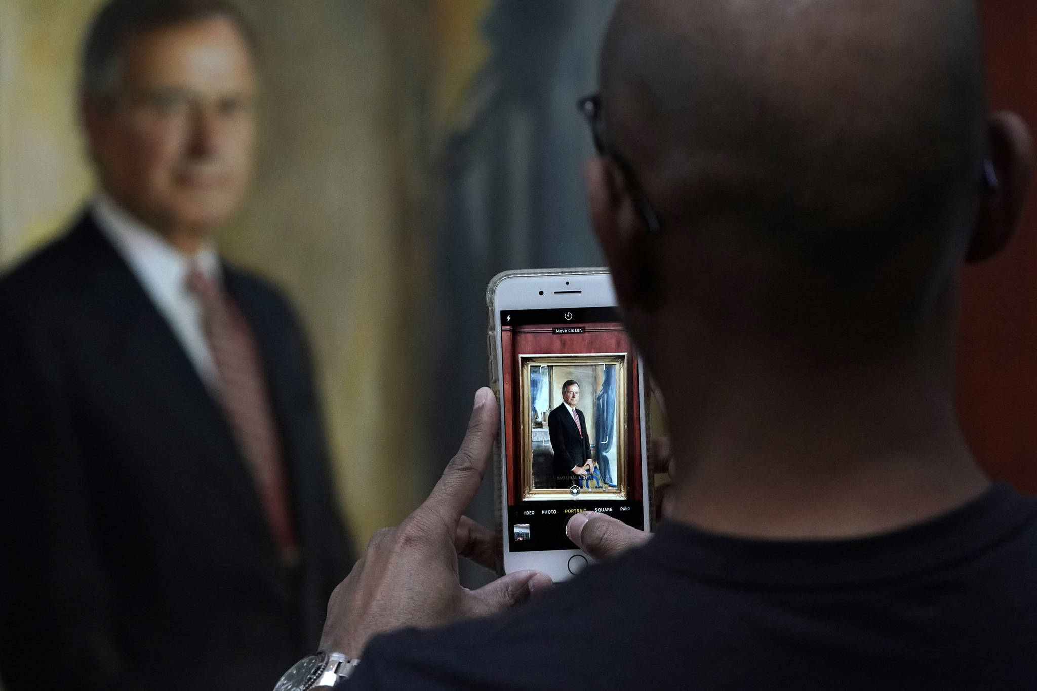 Ayman Tahir takes a photo of a painting of George H.W. Bush inside the George H.W. Bush Library and Museum Saturday, Dec. 1, 2018, in College Station. Bush has died at age 94. Family spokesman Jim McGrath says Bush died shortly after 10 p.m. Friday, Nov. 30, 2018, about eight months after the death of his wife, Barbara Bush. (David J. Phillip | Associated Press)