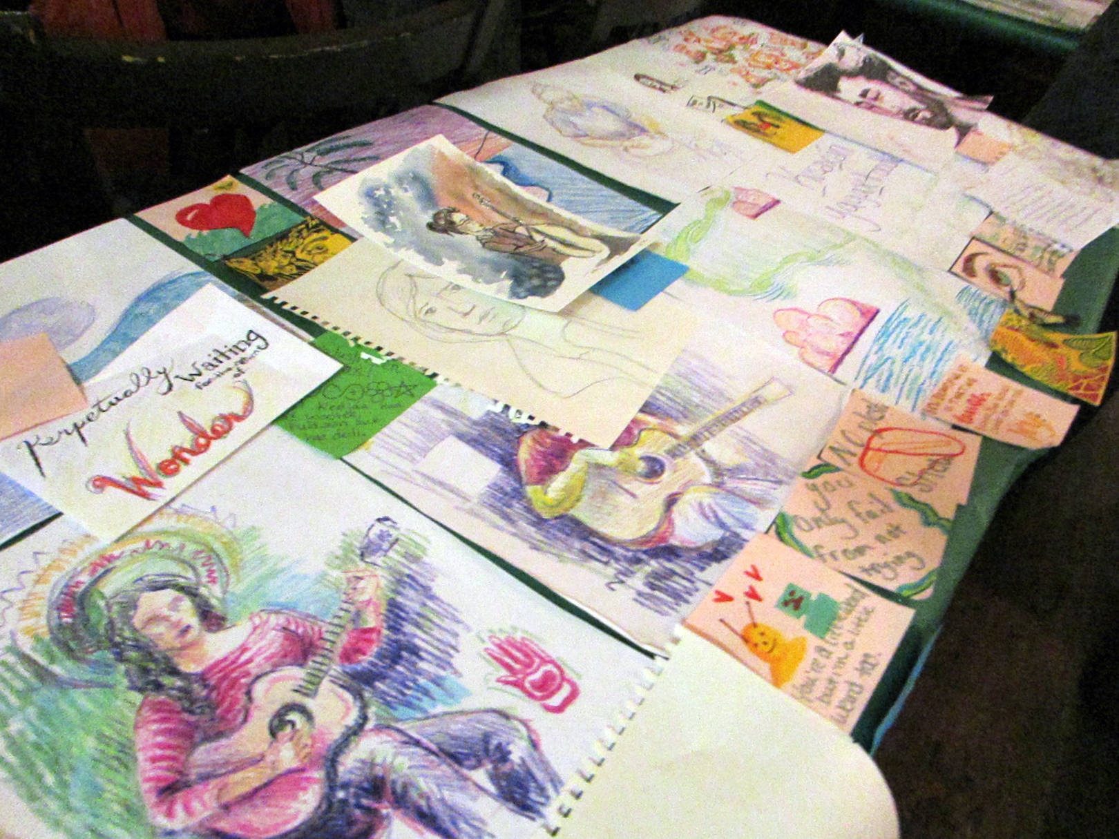 Folding tables were covered in art made during past Mountainside Open Mics during the final show of the season, Thursday, Dec. 13, 2018. (Ben Hohenstatt | Capital City Weekly)