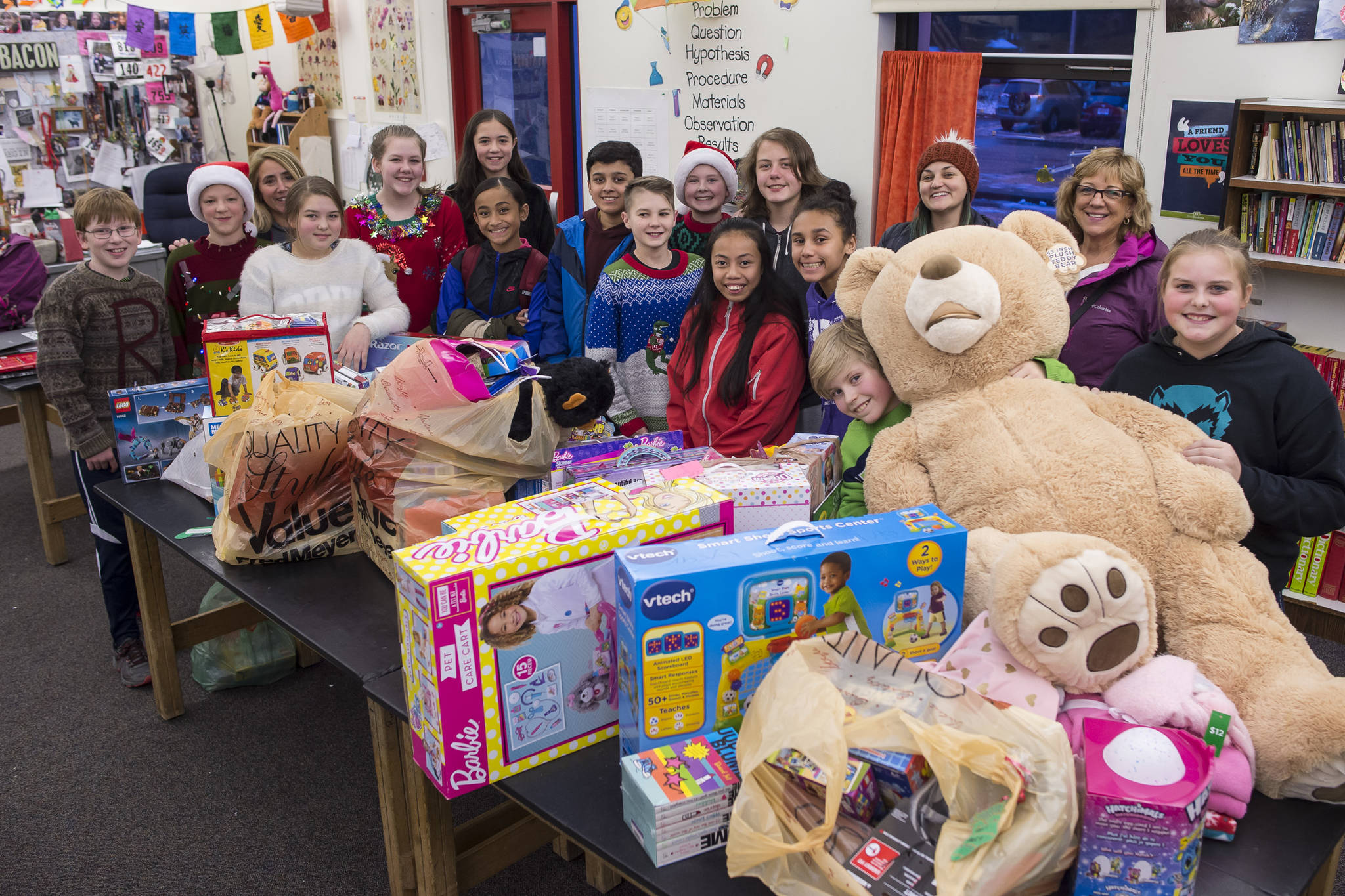 Floyd Dryden Middle School student council members gather around toys collected during a drive for Christmas presents to children in need at FDMS on Monday, Dec. 17, 2018. The toys and gift cards were handed over to the Alaska Department of Health and Social Services’ Office of Children Services for distribution. (Michael Penn | Juneau Empire)