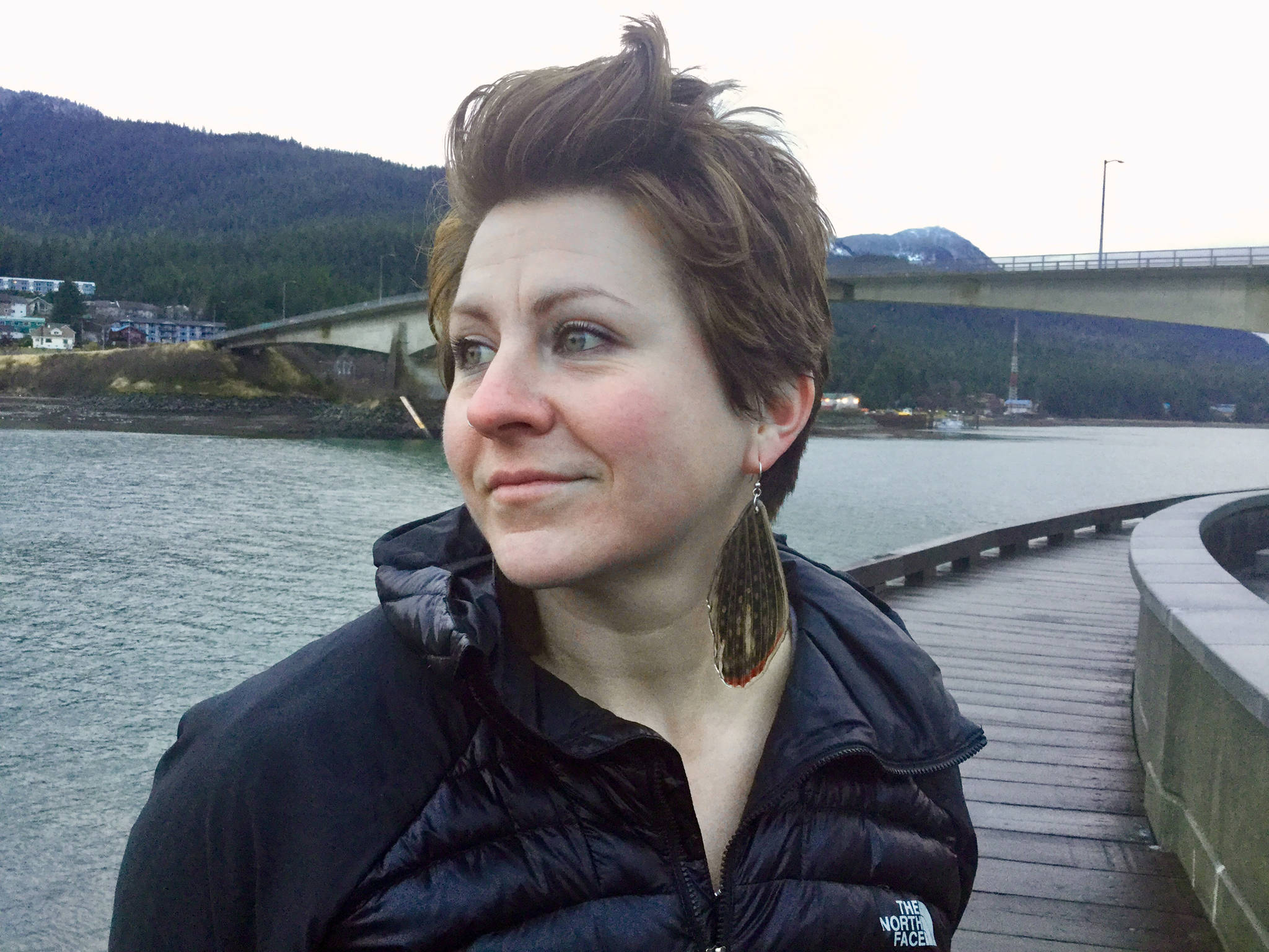 Artist Julienne Pacheco, who makes jewelry out of fish skin and other natural materials, poses on the downtown Juneau Seawalk with earrings made out of arctic grayling dorsal fins. (Courtesy Photo | Julienne Pacheco)