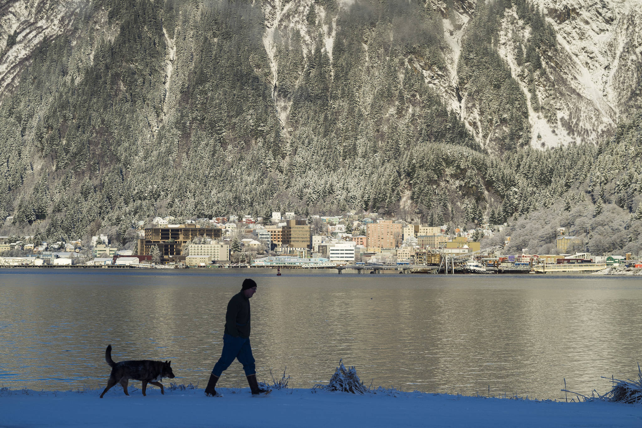 Mike Donnellan takes a short walk in the fresh snow near the Mike Pusich Douglas Harbor with his dog, Denali, on Thursday, Dec. 20, 2018. (Michael Penn | Juneau Empire)