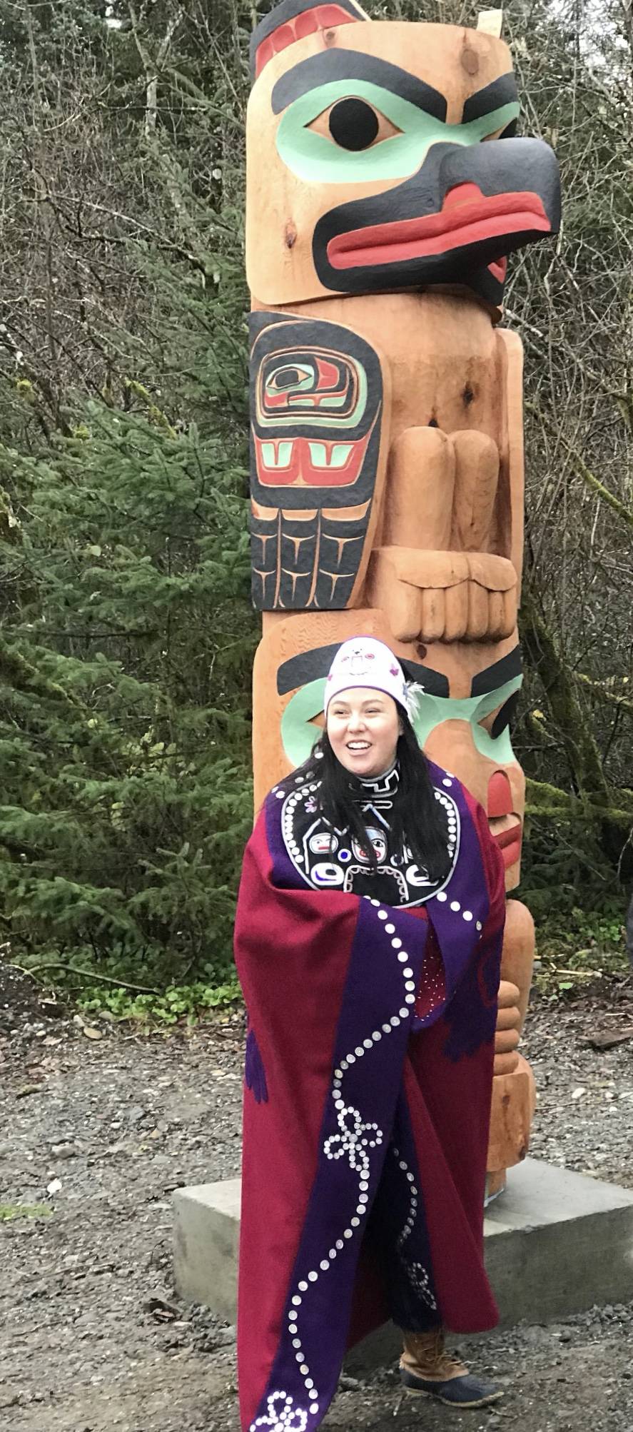 Alison Marks stands with a thermos-clutching totem she carved that was raised at Yakutat on Tuesday, Oct. 27, 2018. (Courtesy photo | Thom Landgreen)