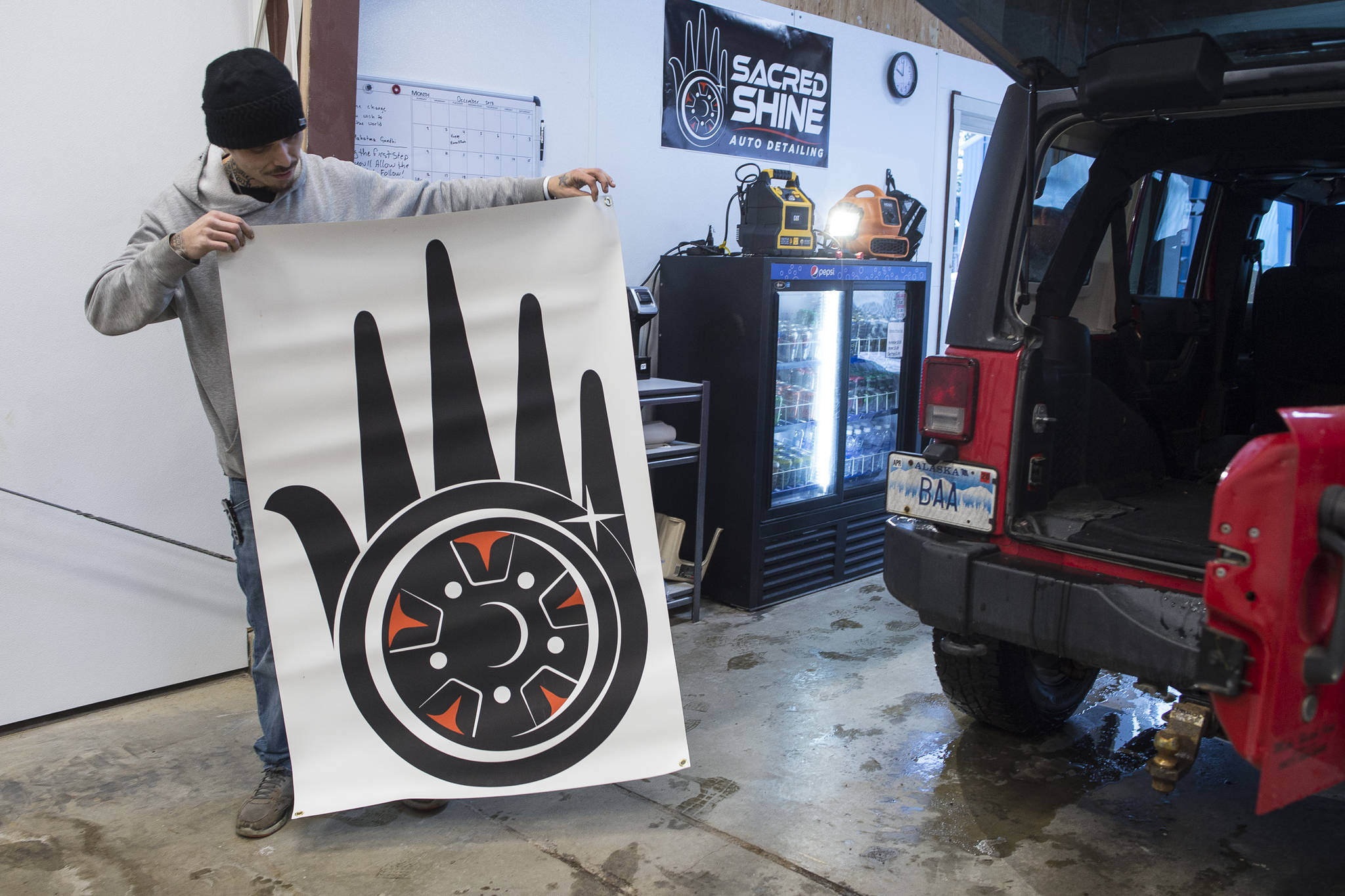 Lead Detailer Calvin Olsen shows the logo developed for a new auto detailing business called Sacred Shine offered by the Central Council of the Tlingit and Haida Indian Tribes of Alaska on Friday, Dec. 21, 2018. The logo was designed by tribal member Miciana Hutcherson. (Michael Penn | Juneau Empire)