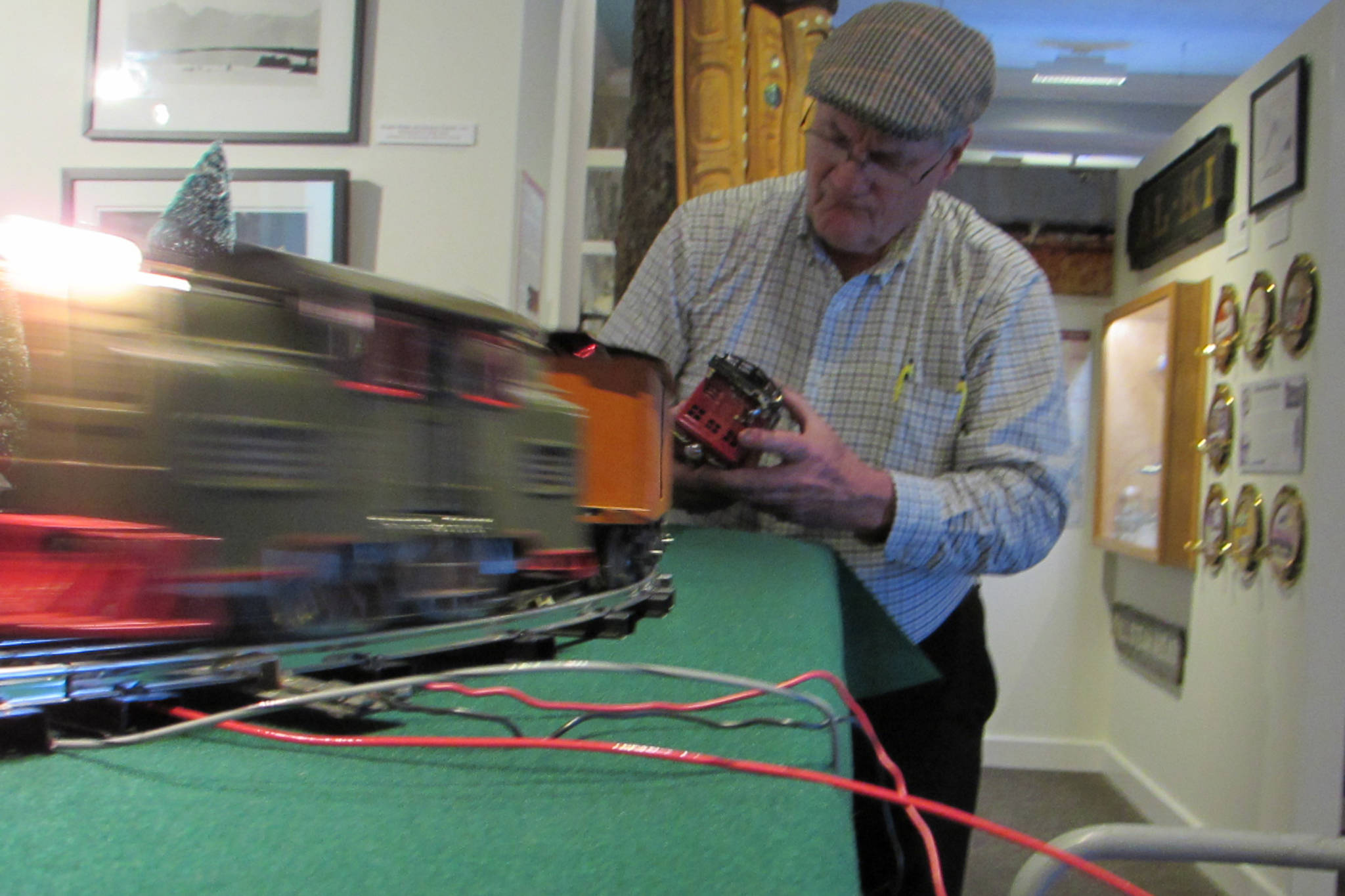 Mike Orford adjusts one of his model trains while another zips along its tracks in the Juneau-Douglas City Museum, Saturday, Dec. 22,2018. (Ben Hohenstatt | Capital City Weekly)
