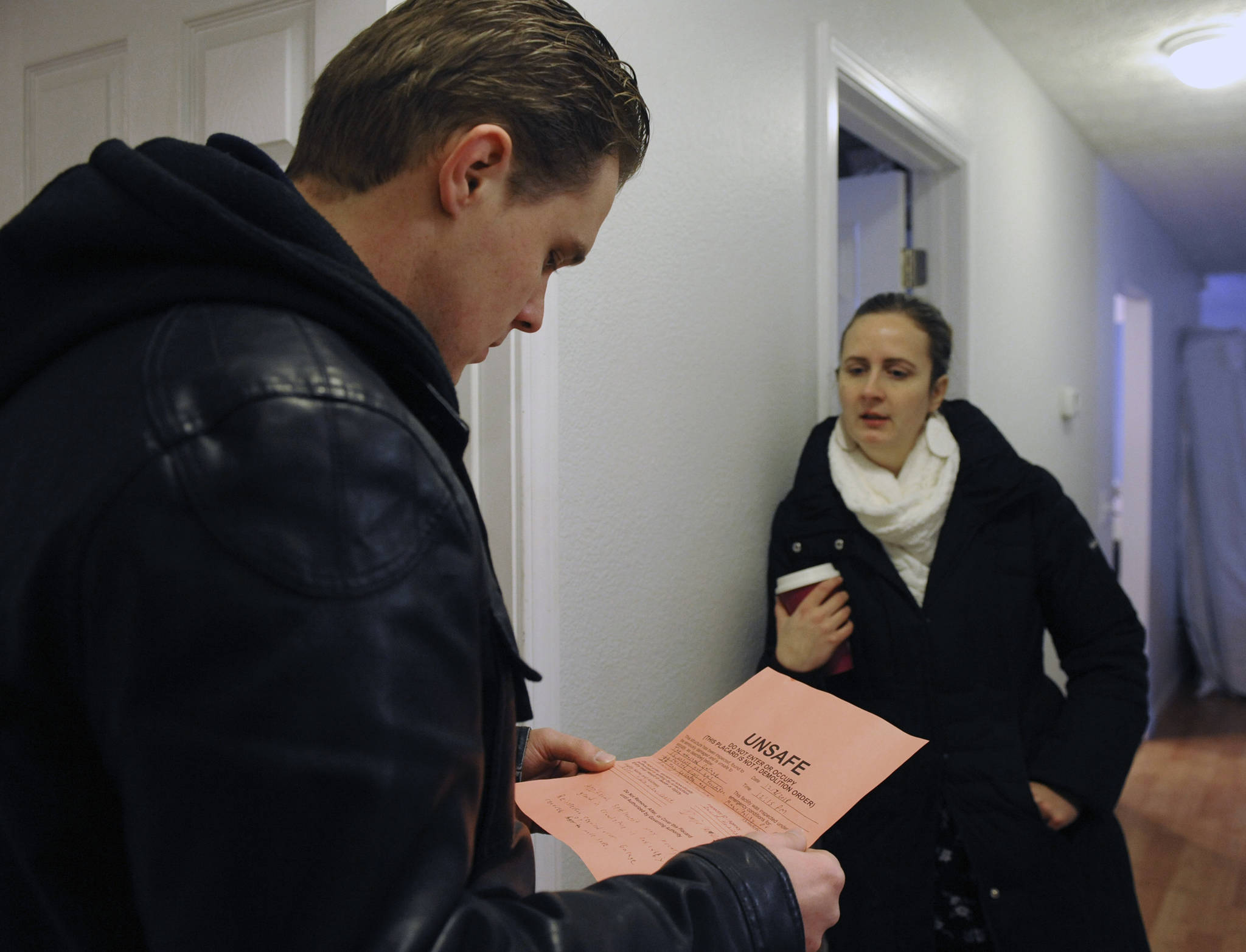 In this Dec. 13, 2018 photo, Albert Schoonbeek and Candice Roberson talk about the Unsafe tag their home received after an engineer inspected their home in East Anchorage, Alaska, after the earthquake. Schoonbeek and Roberson are among an unknown number of people displaced by the Nov. 30 earthquake. (Anne Raup | Anchorage Daily News via the Associated Press)