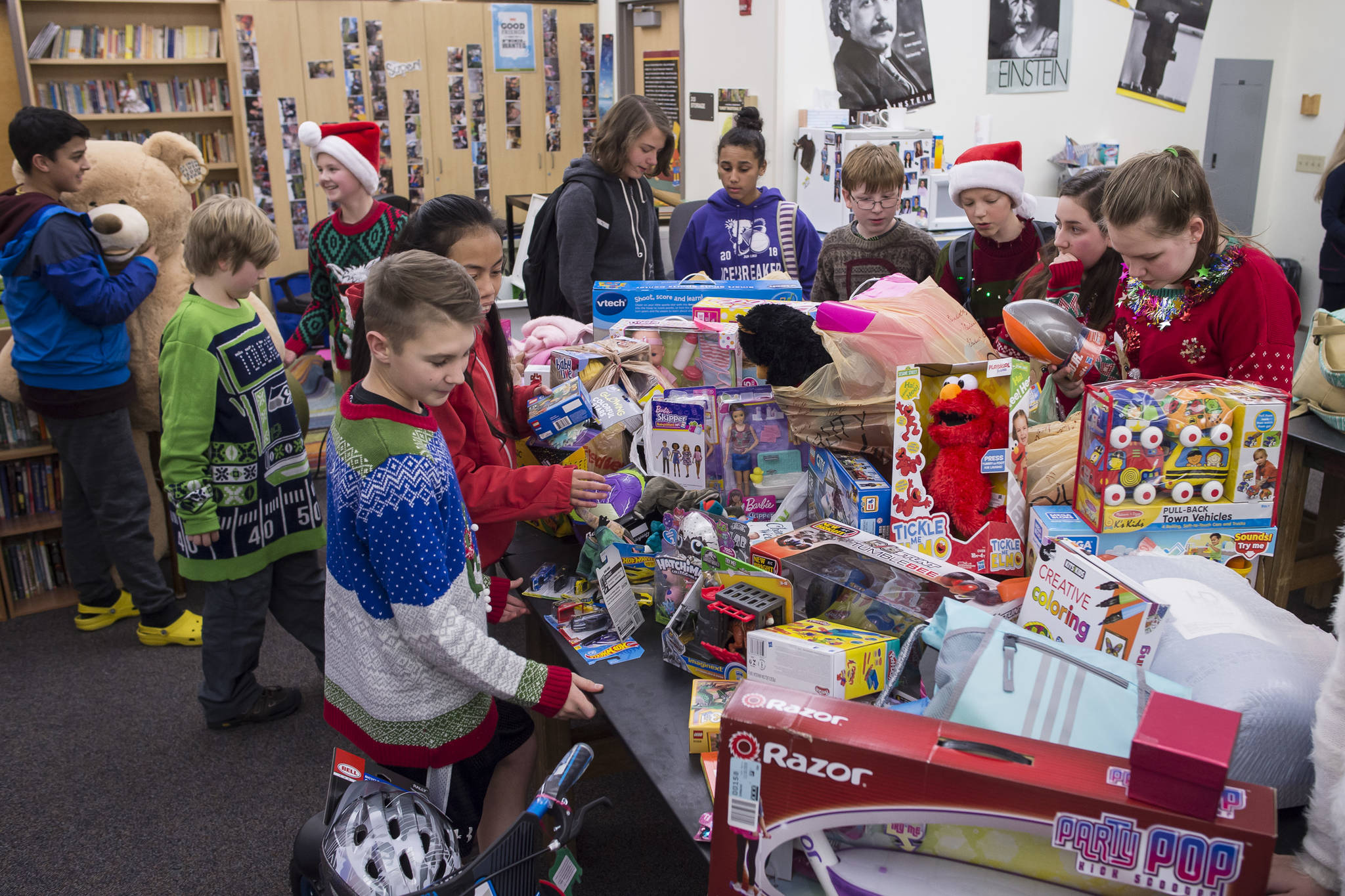 Floyd Dryden Middle School student council members gather around toys collected during a drive for Christmas presents to children in need at FDMS on Monday, Dec. 17, 2018. The toys and gift cards were handed over to the Alaska Department of Health and Social Services’ Office of Children Services for distribution. (Michael Penn | Juneau Empire)