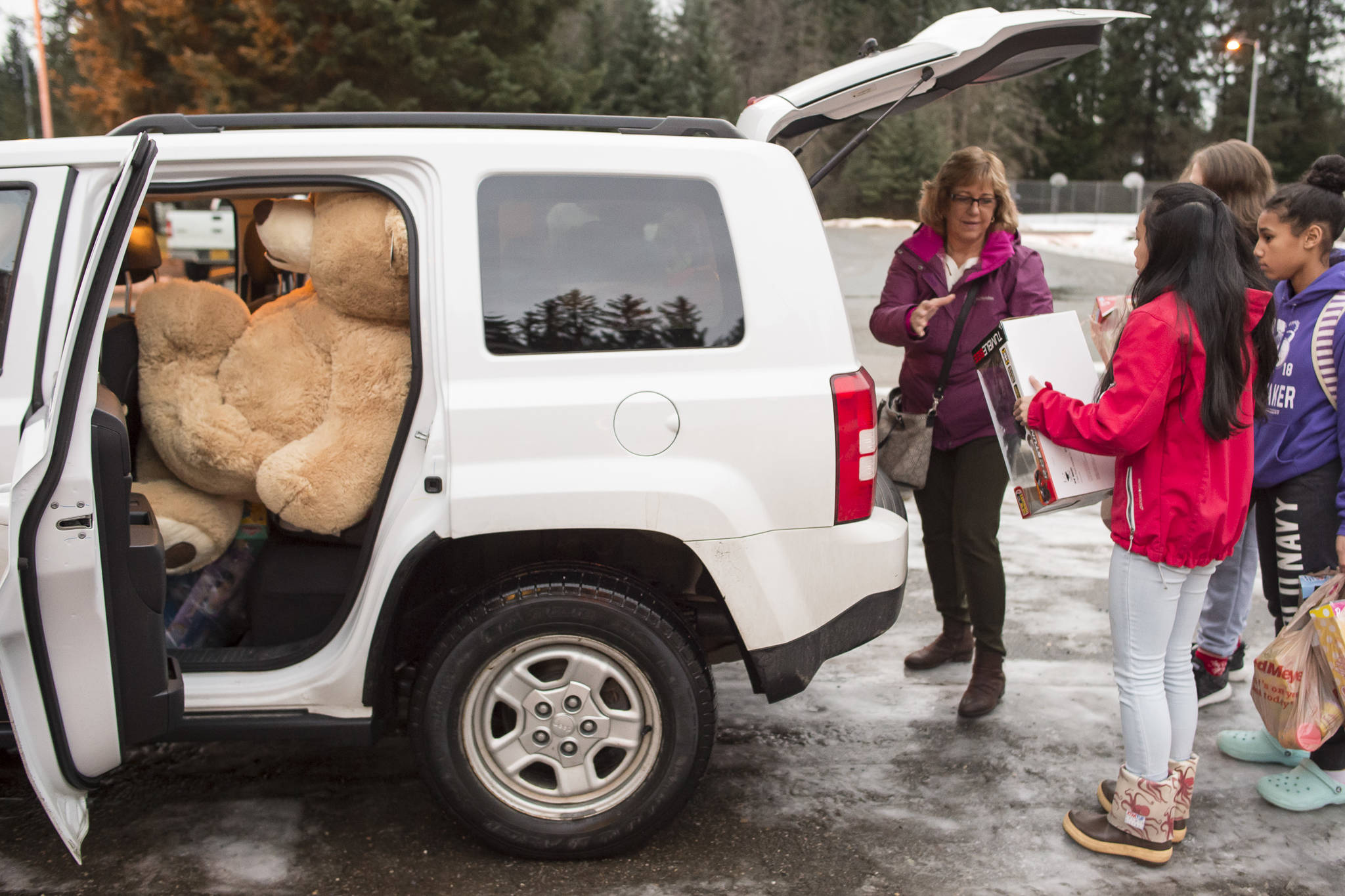 Lynn Logan, of the Alaska Department of Health and Social Services’ Office of Children Services, is helped load Christmas presents collected by Floyd Dryden Middle School student council members at FDMS on Monday, Dec. 17, 2018. The student organized a school money and toy drive for the OCS program to help needy children. (Michael Penn | Juneau Empire)