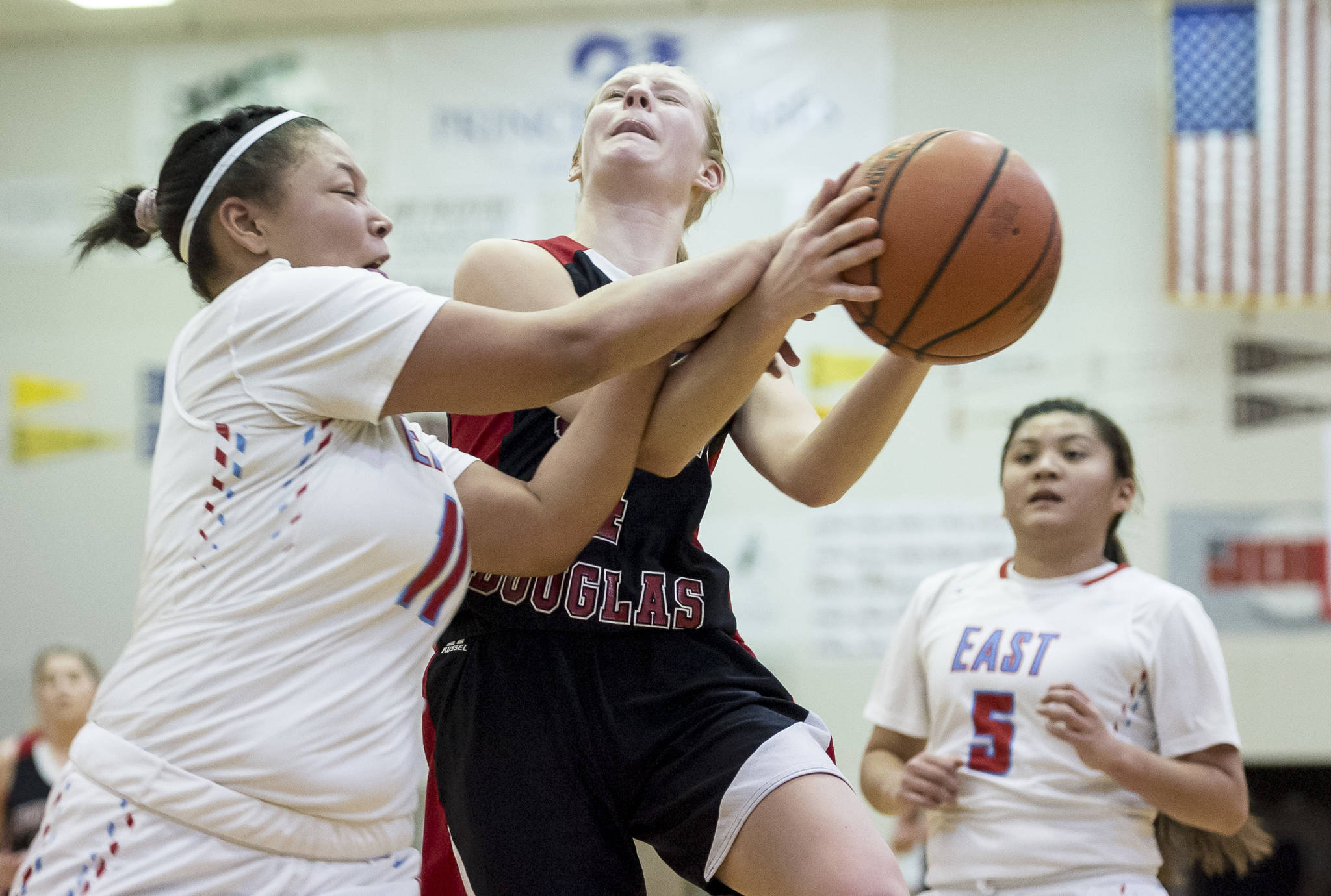Juneau-Douglas’ Sadie Tuckwood is fouled on the way to the basket by East’s Amari Brown at the Princess Cruises Capital City Classic at Juneau-Douglas High School on Saturday, Dec. 29, 2018. East won 57-55. (Michael Penn | Juneau Empire)