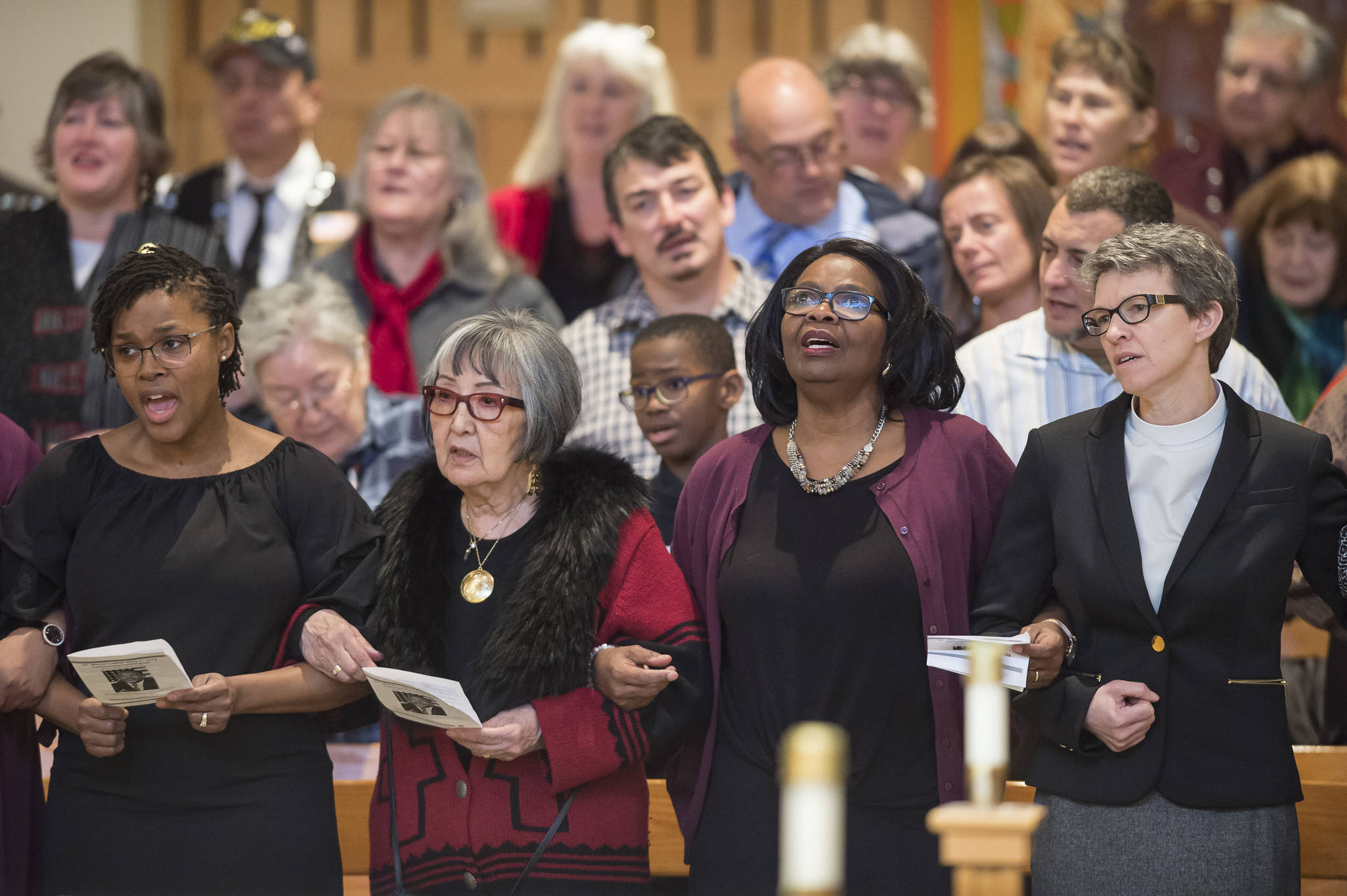 Juneau residents link arms as they sing “We Shall Overcome” at the Dr. Martin Luther King Jr. 2019 Community Celebration at St. Paul’s Catholic Church on Monday, Jan. 21, 2019. In the front row from left are: Latarsha McQueen, of the Black Awareness Association, Dr. Rosita Worl, president of the Sealaska Heritage Institute, Michelle Monts, former president of the Black Awareness Association, and Pastor Tari Stage-Harvey, of the Shepherd of the Valley Lutheran Church. (Michael Penn | Juneau Empire)
