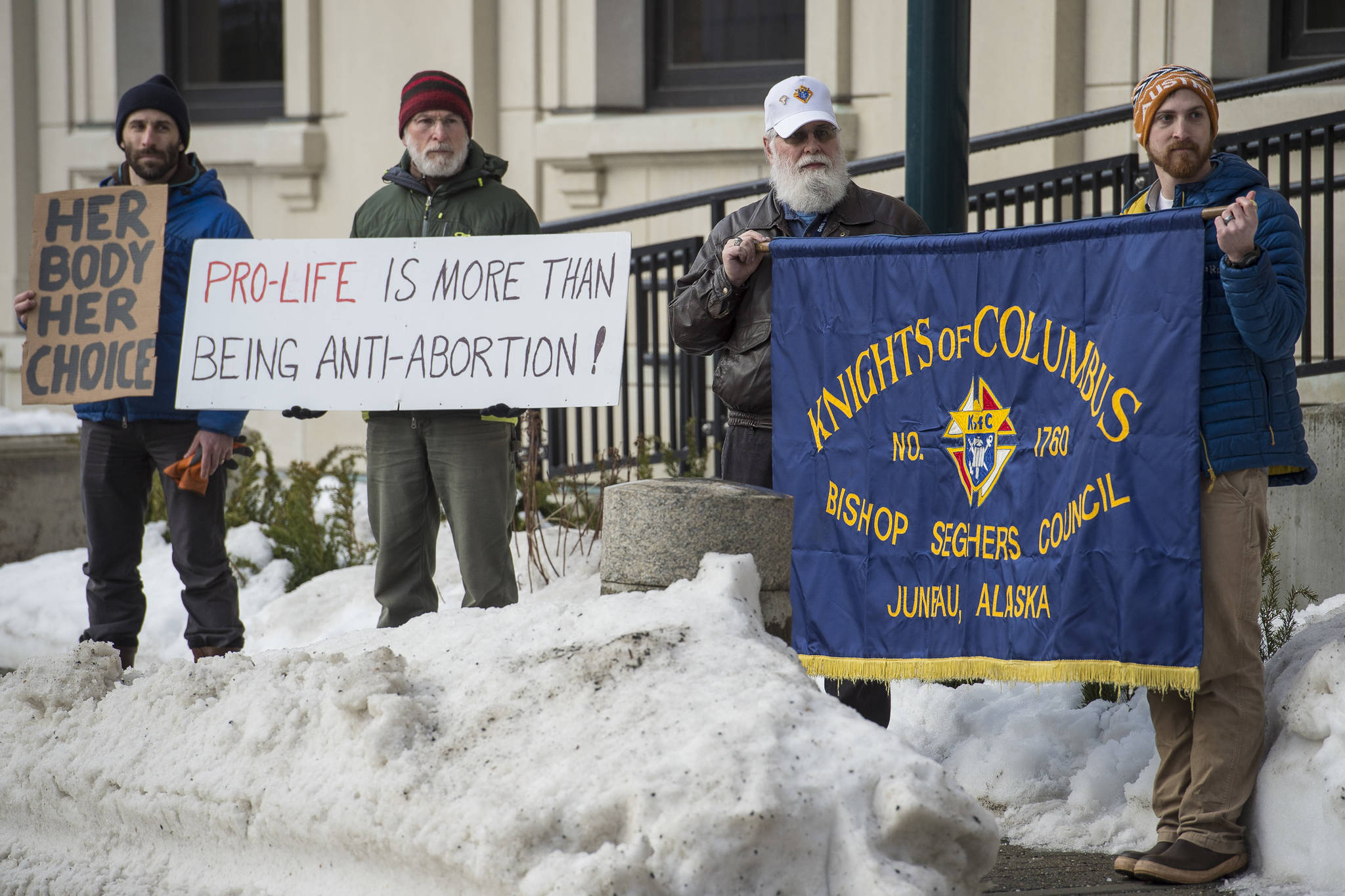 Paul Desloover, second from left, and his son, Dan, left, hold a counter protest as Leo DeMeo and Andrew Klausner, of the Knights of Columbus attend the Alaskans for Life, Inc. annual Rally for Life in front of the Capitol on Tuesday, Jan. 22, 2019. (Michael Penn | Juneau Empire)