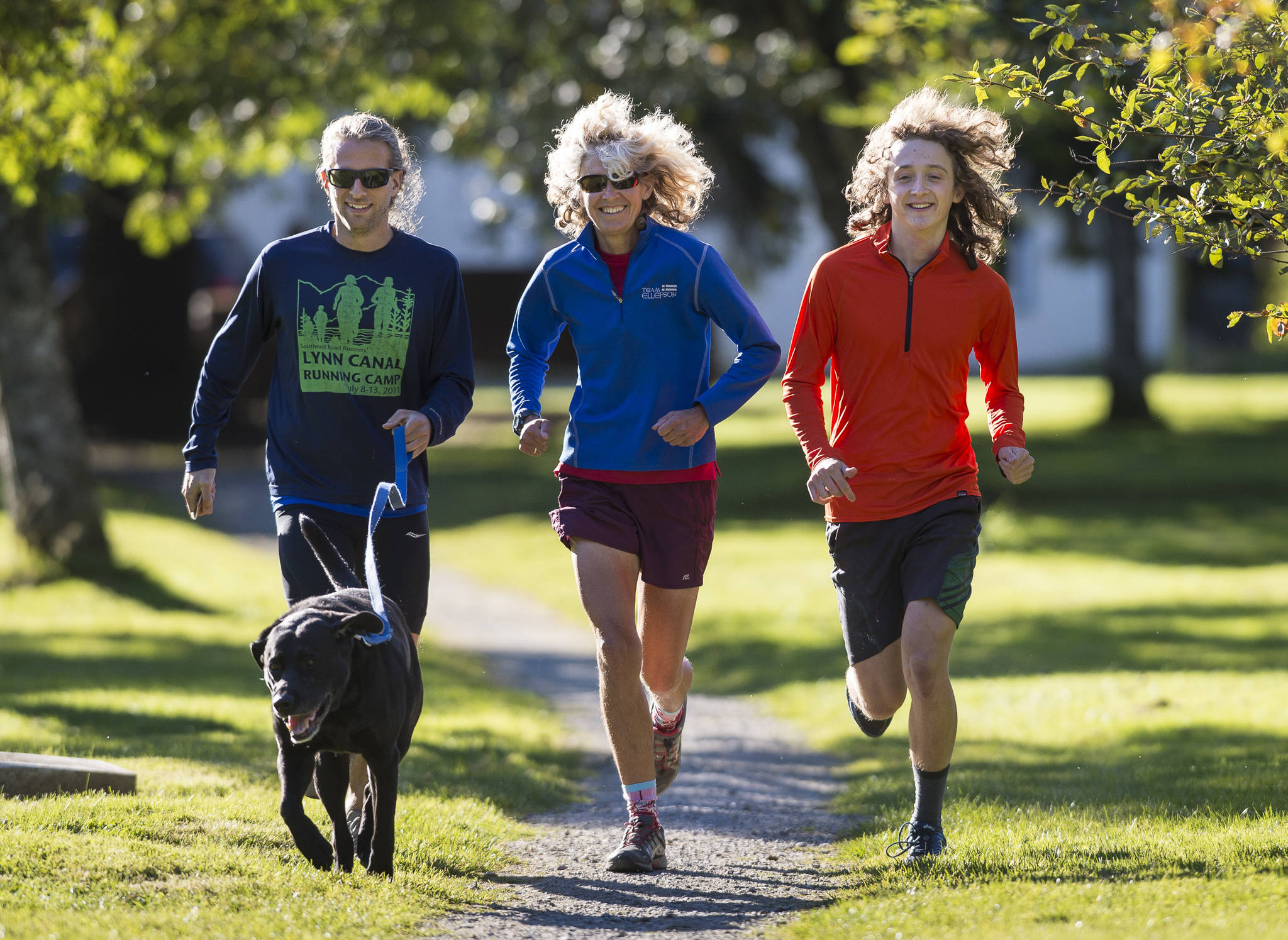 Merry Ellefson, center, runs with her son, Arne Ellefson-Carnes, right, and co-coach Tristan Knutson-Lombardo during Juneau-Douglas High School cross country practice on Wednesday, Sept. 19, 2018. (Michael Penn | Juneau Empire File)
