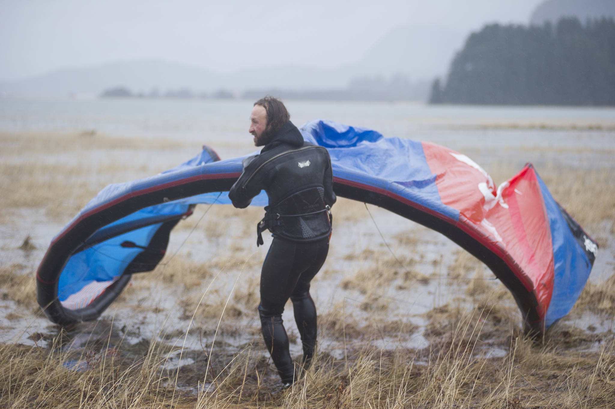 Rob Cadmus drags his kite back to shore after kiteboarding in the Gastineau Channel on Sunday, Dec. 9, 2018. (Nolin Ainsworth | Juneau Empire)