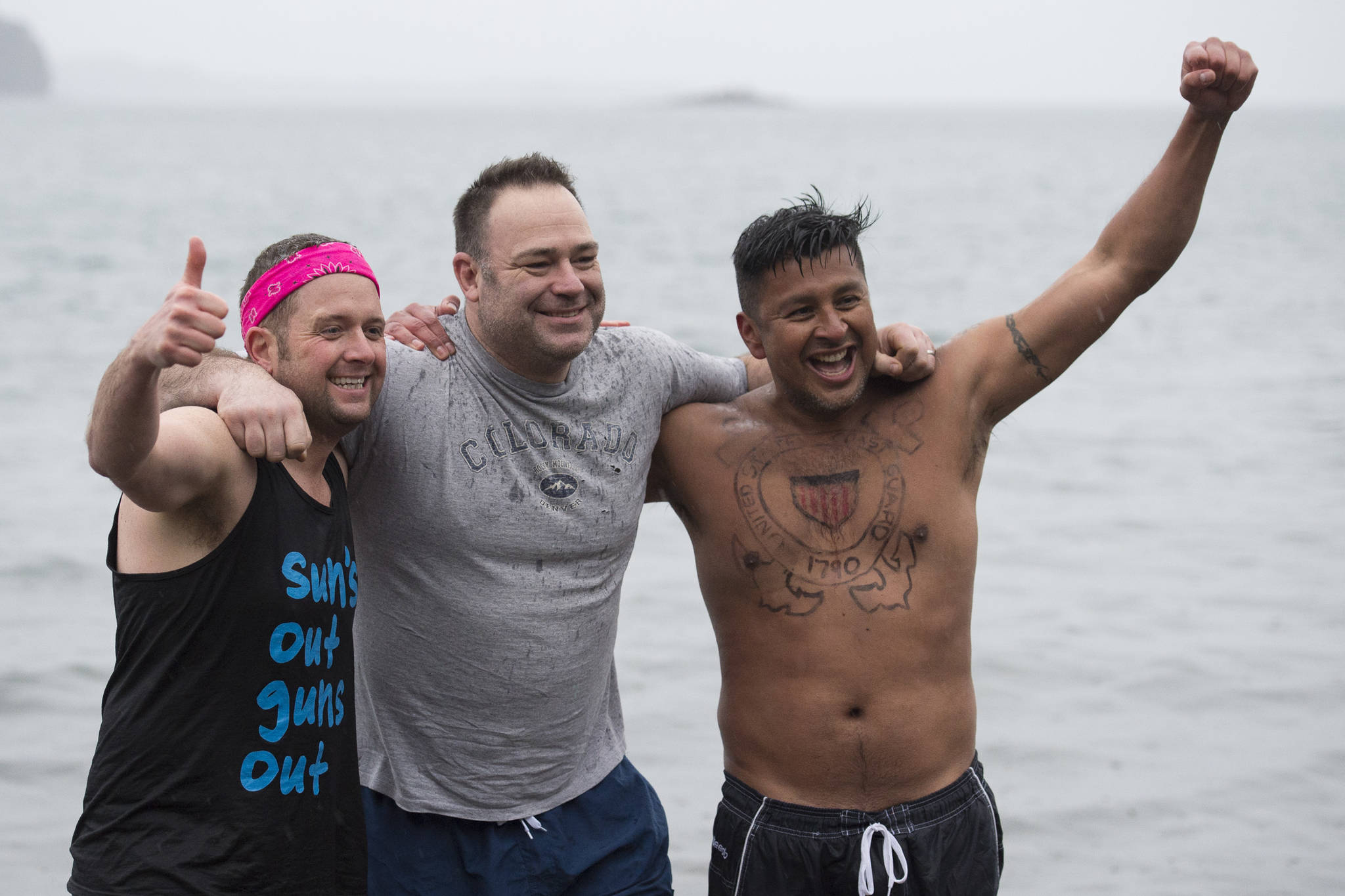 U.S. Coast Guard members John Dale, left, Chris Coutu, center, and Marvin Pena pose for a picture before taking to the frigid waters at Auke Bay Recreation Area for the annual Juneau Polar Bear Dip on Tuesday, Jan. 1, 2019. Nearly 200 people took the plunge to start off the new year. (Michael Penn | Juneau Empire)