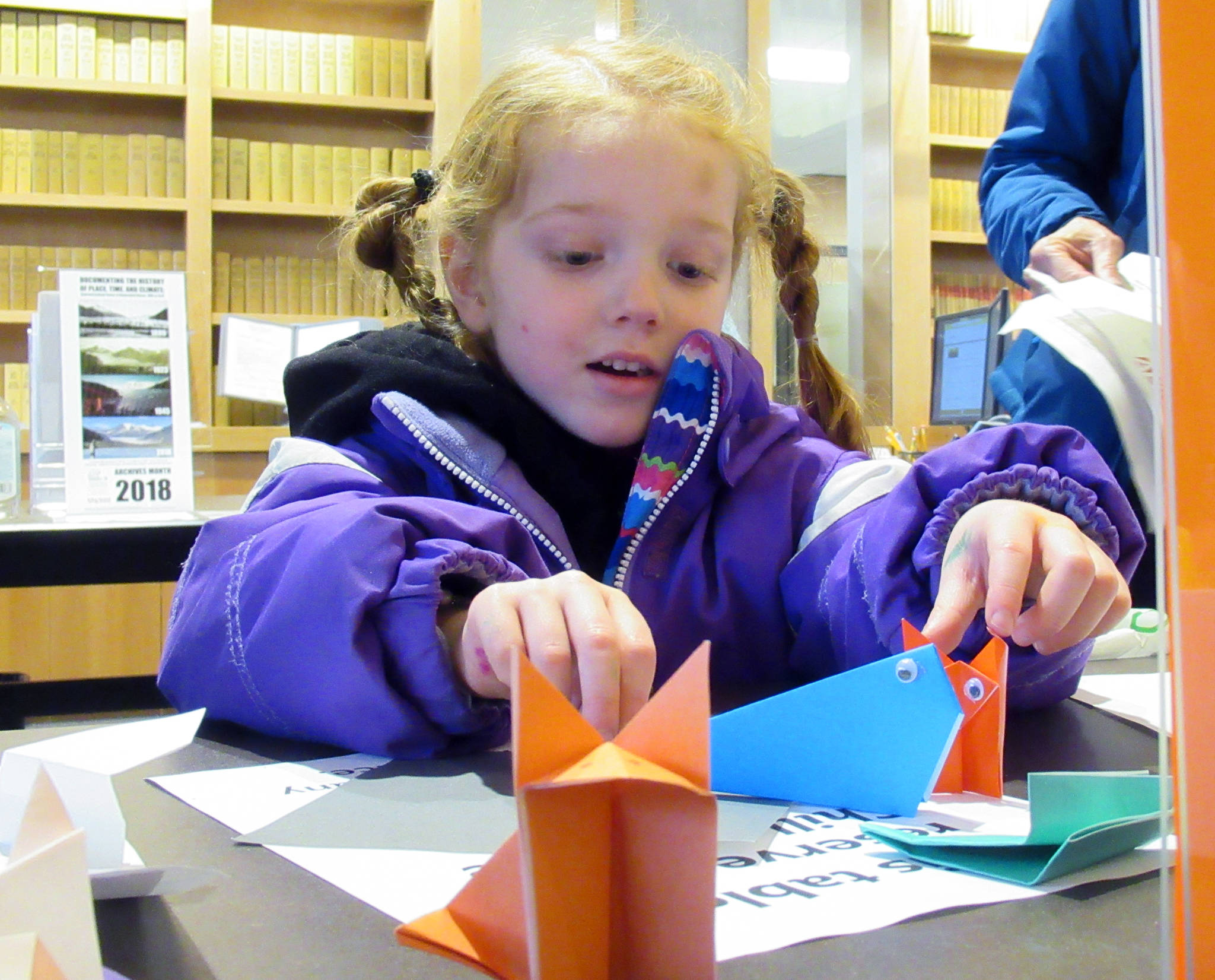 Wren Mesdag, 4, finishes up an origami whale during the Family Fair Friday, Jan.4, 2019. One of the stations at the event allowed children to fold paper into shapes resembling Alaskan animals. (Ben Hohenstatt | Capital City Weekly)