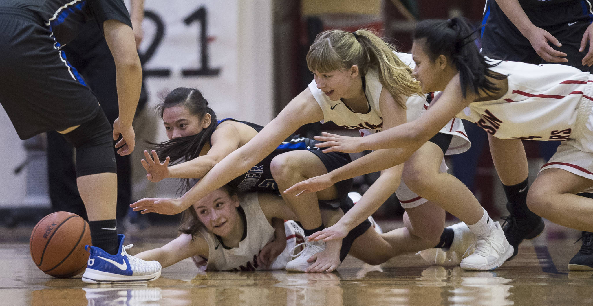 Thunder Mountain’s Kyaye Garcia, left, dives for a loose ball against Juneau-Douglas’ Kiana Potter, bottom left, Caitlin Pusich and Alyxn Bohulano, right, at JDHS on Friday, March 3, 2018. JDHS won 53-33.