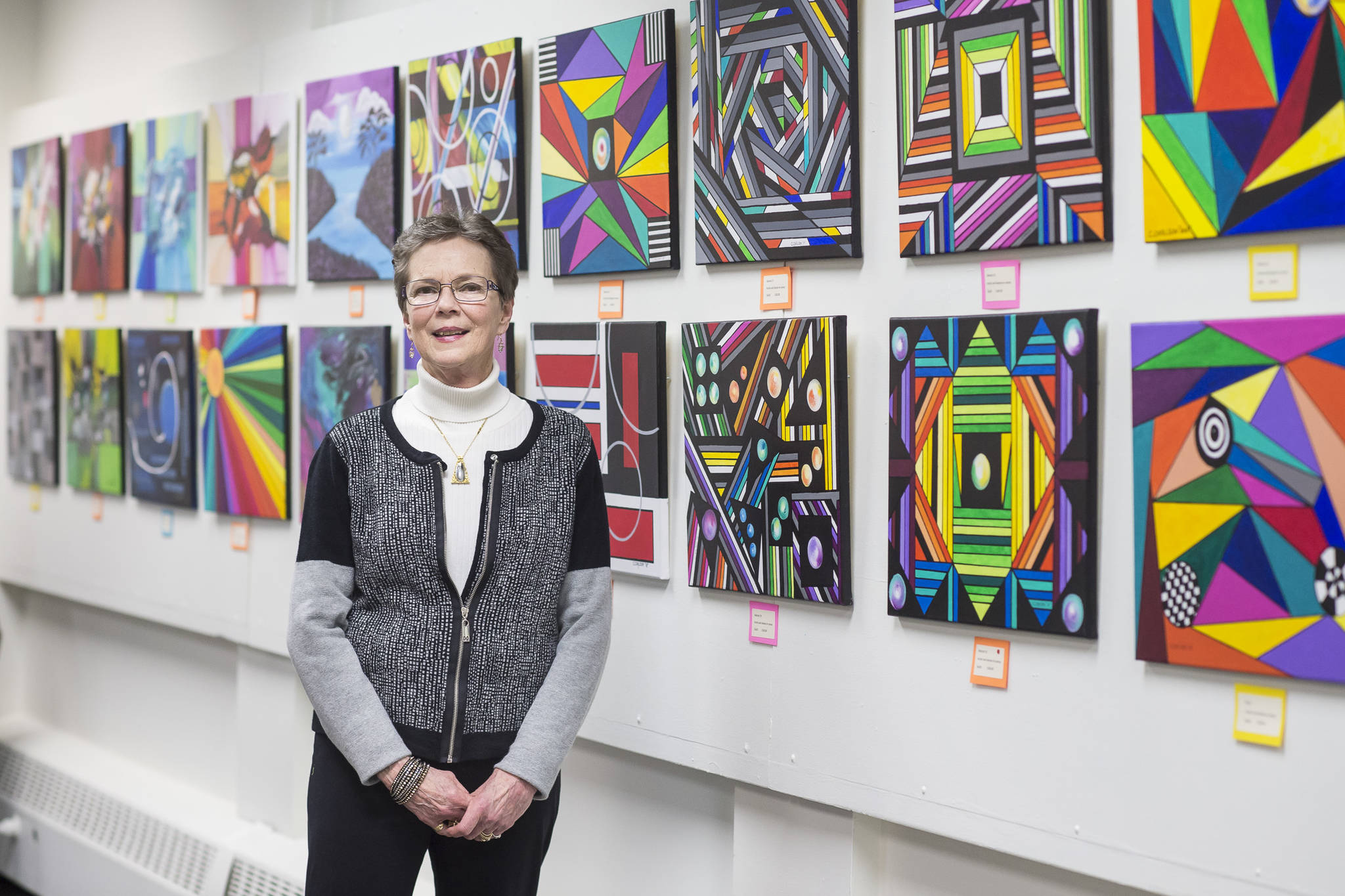 Carol Carlson stands with her paintings on display at the Juneau Arts & Humanities Council during First Friday on Friday, Jan. 4, 2019. (Michael Penn | Juneau Empire)