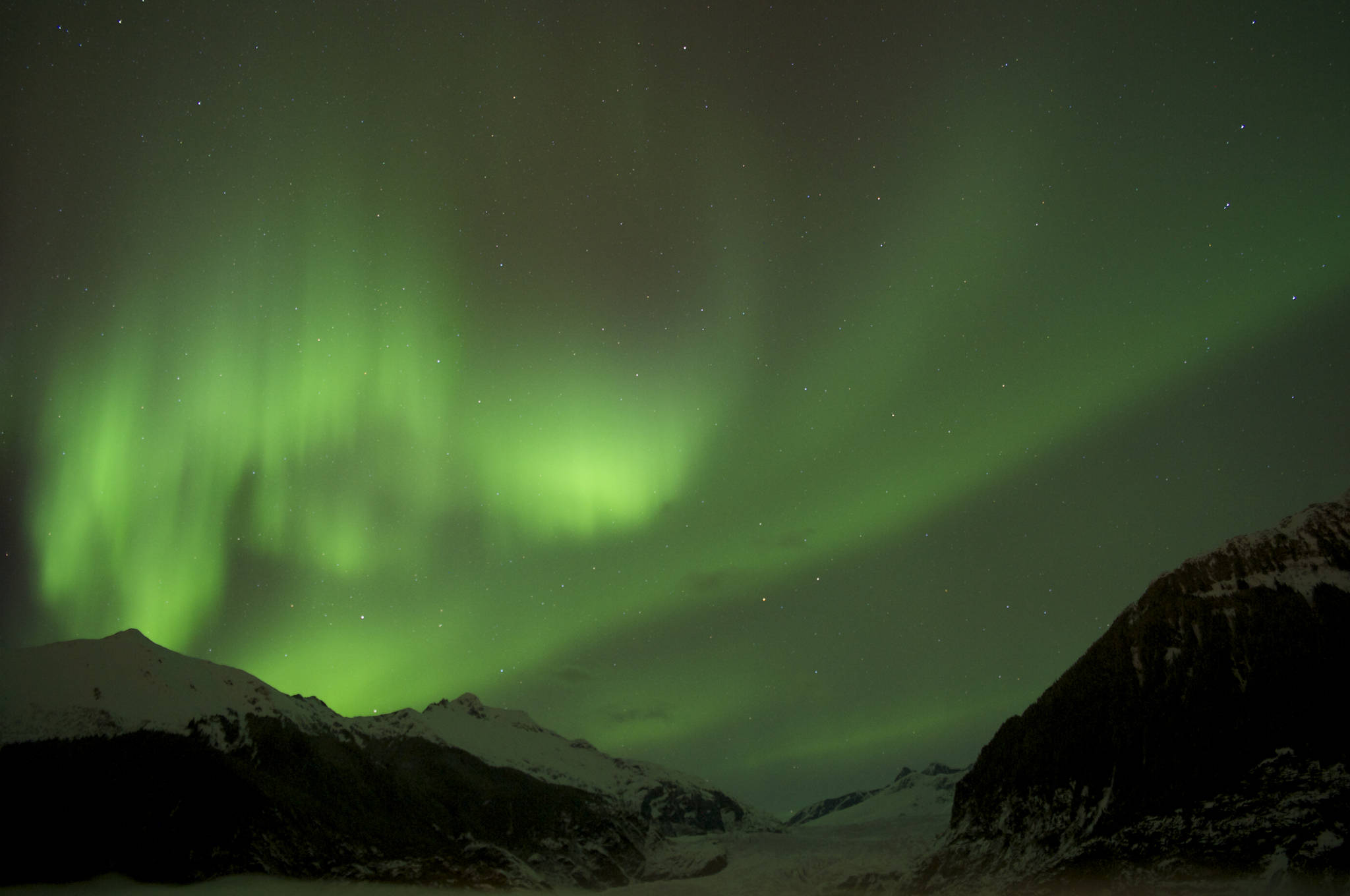 The Aurora Borealis glows over the Mendenhall Glacier in this file photo from February 2014. (Michael Penn | Juneau Empire File)