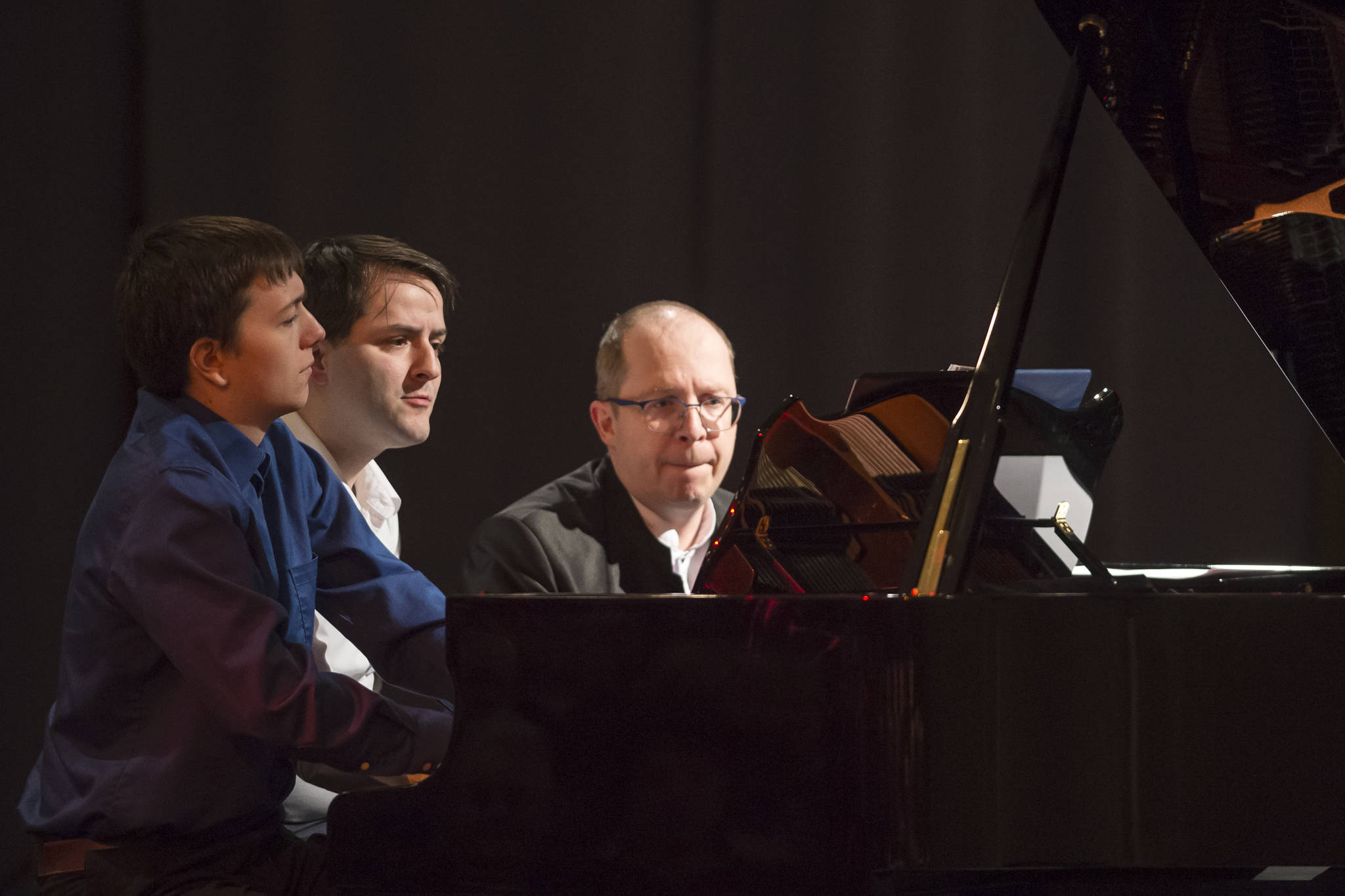 Kyle Farley-Robinson, left, Jon Hays, center, and Dr. Alexander Tutunov play “Romance And Waltz For Six Hands Piano” by Sergei Rachmaninoff during the Juneau Piano Series featuring Tutunov at the Juneau Arts & Culture Center on Friday, Jan. 18, 2019. (Michael Penn | Juneau Empire)
