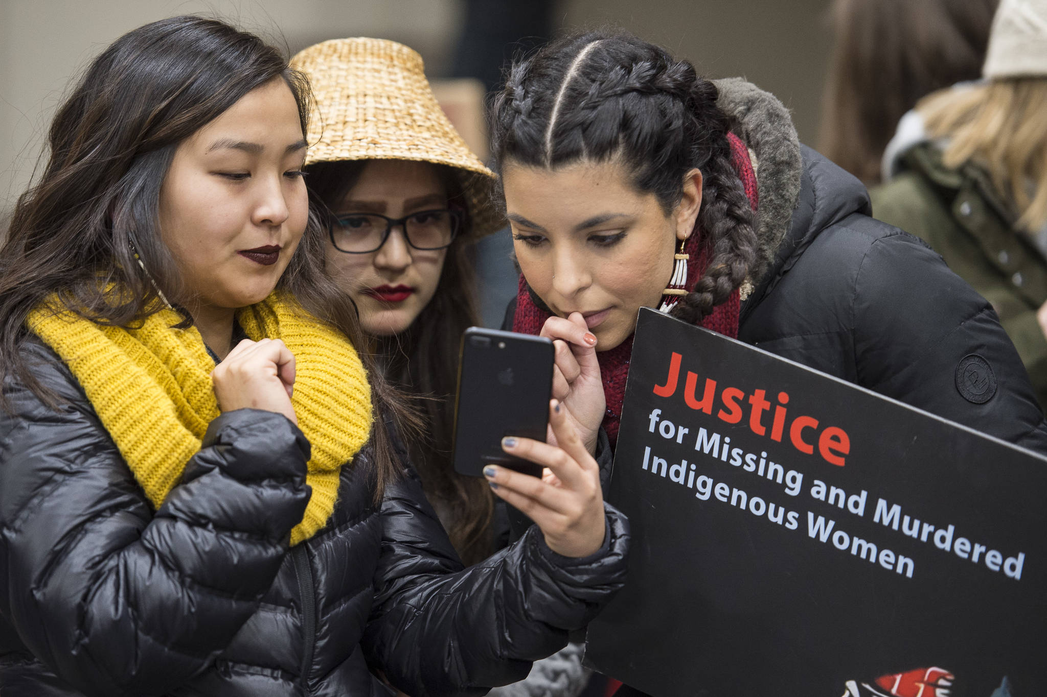 Laytlynne Lewis, left, Lyndsey Brollini, center, and Huynter Meachum check it after the Women’s March on Juneau at Centennial Hall on Saturday, Jan. 19, 2019. (Michael Penn | Juneau Empire)