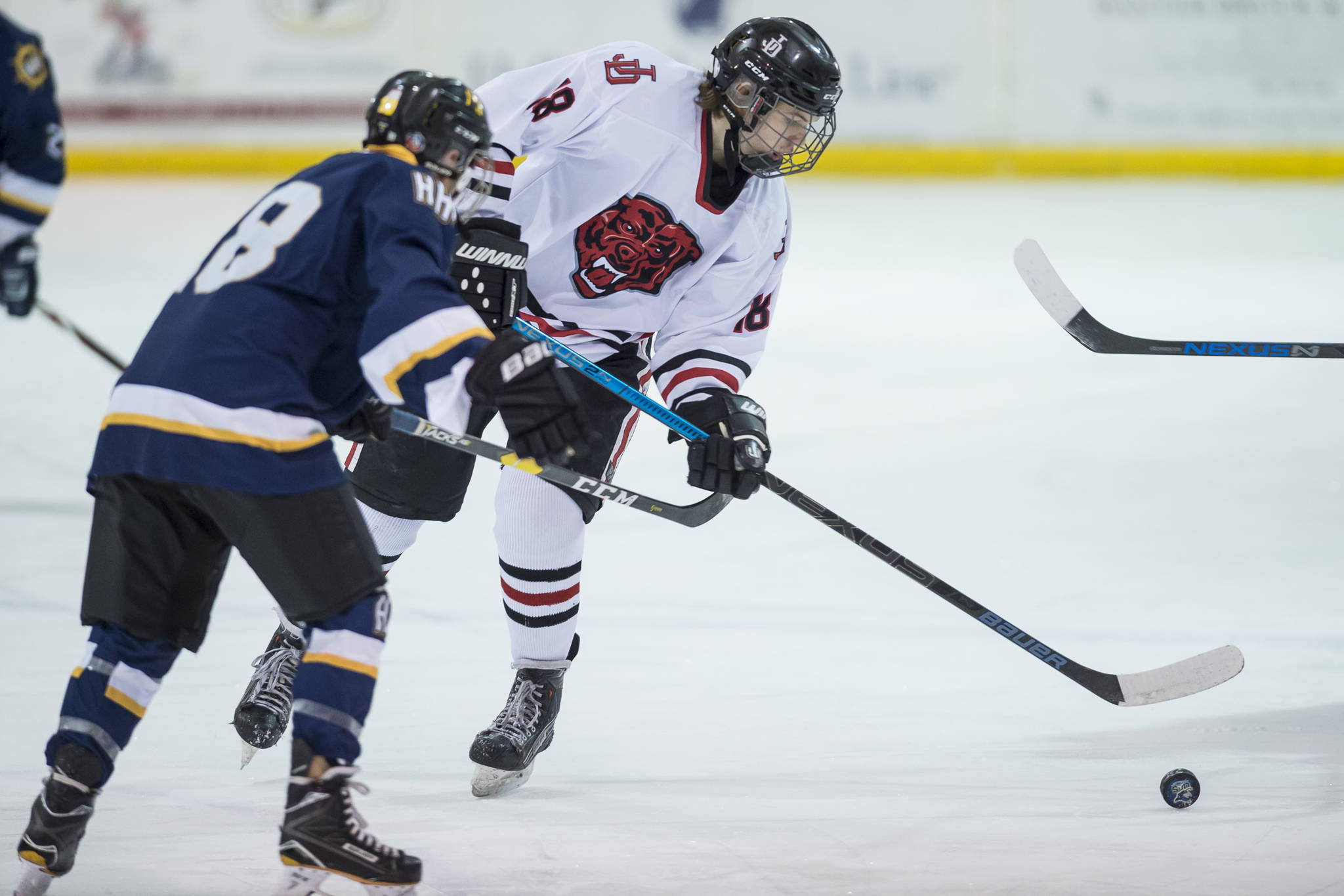 Juneau-Douglas’ Dalton Hoy, right, moves the puck against Homer’s Bergen Knutson at Treadwell Arena on Friday, Jan. 18, 2019. JDHS and Homer square off in the ASAA First National Cup state hockey semifinals on Friday in the Curtis Menard Sports Complex in Wasilla. (Michael Penn | Juneau Empire File)