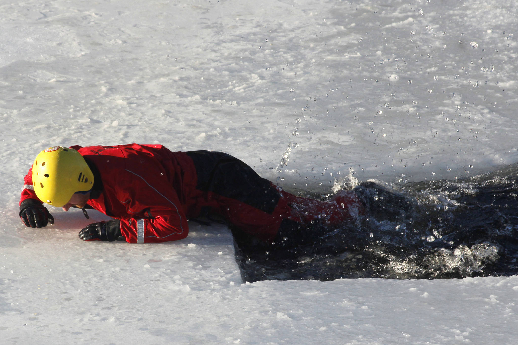 Pete Boyd, a member of Capital City Fire/Rescue’s Special Teams unit, demonstrates how to get out of the water if you’ve fallen through the ice. The demonstration, which took place Saturday at the Mendenhall Glacier Visitor Center, drew about 60 people and included a presentation with tips on how to be prepared in case you or another person falls through the ice. (Alex McCarthy | Juneau Empire)