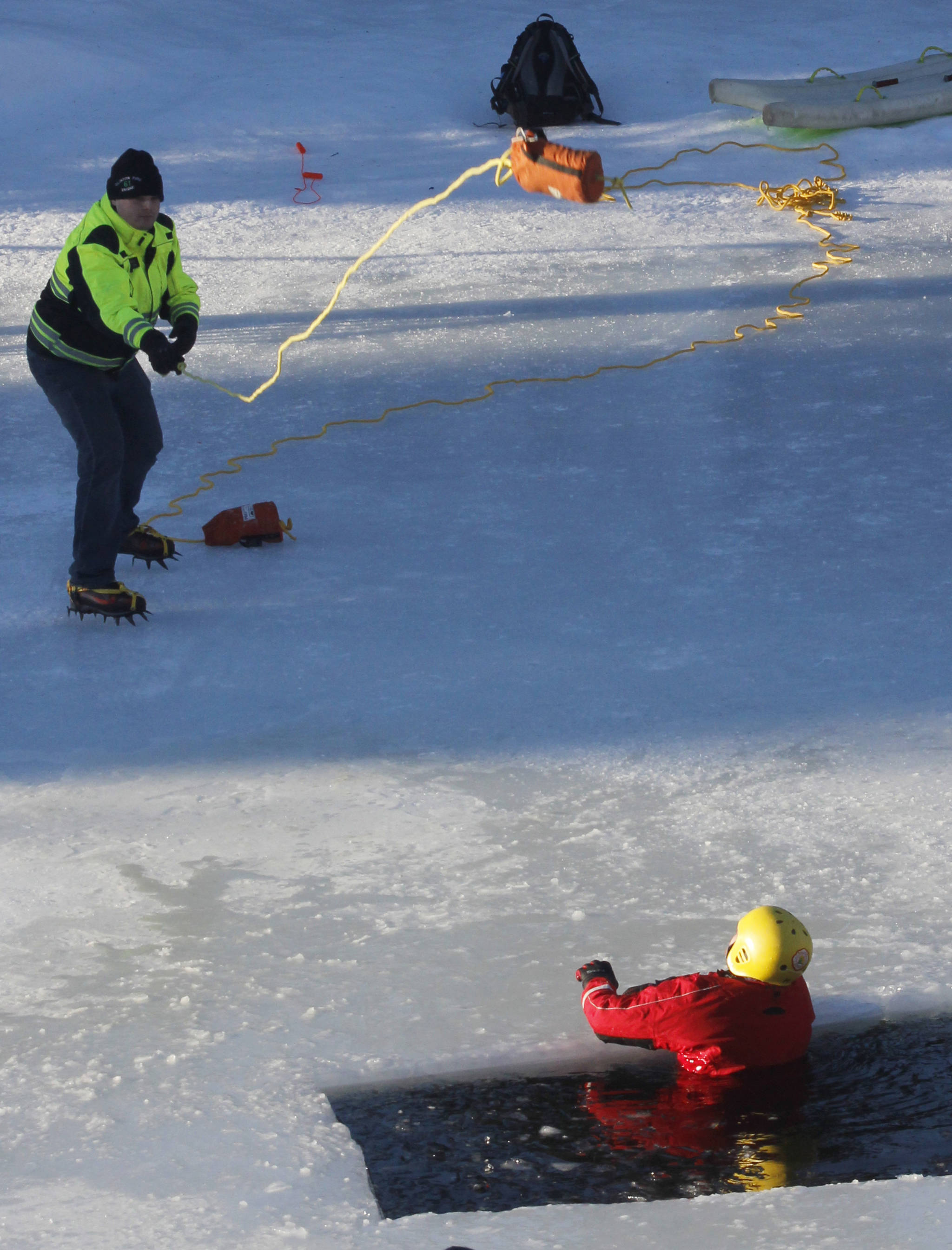 Capital City Fire/Rescue Firefighter and Paramedic Cory Hutchison throws a rescue rope to CCFR Special Teams Member Pete Boyd during a demonstration on how to get out of the water if you’ve fallen through the ice. The demonstration, which took place Saturday at the Mendenhall Glacier Visitor Center, drew about 60 people and included a presentation with tips on how to be prepared in case you or another person falls through the ice. (Alex McCarthy | Juneau Empire)