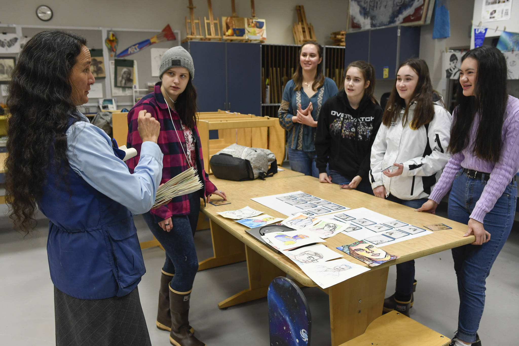Art teacher Angela Imboden, left, talks to students Catherine Ackerman, second from left, Madison Kahle, Tyler Johnson, Alina Renz and Tianah Sangster on Wednesday, Jan. 30, 2019, who participated in a blind contour drawing project and received a signed drawing of a deer’s head on plexiglass by professional contour artist Ian Sklarsky. (Michael Penn | Juneau Empire)