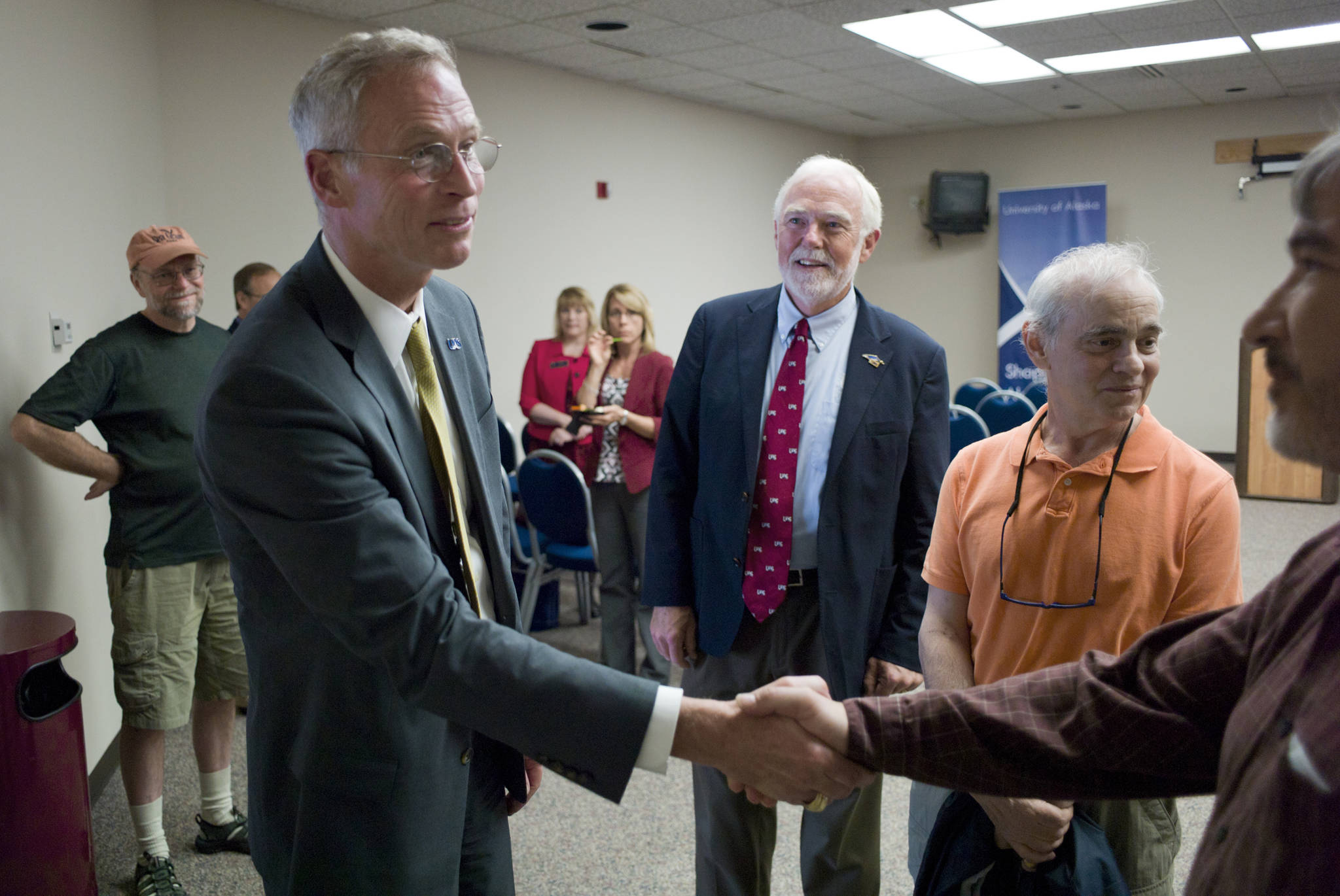 In this July 7, 2015 photo, Dr. Jim Johnsen is greeted by Rep. Sam Kito III, right, as University of Alaska Southeast Chancellor Dr. Richard Caulfield, center, looks on during a gathering at Centennial Hall. (Michael Penn | Juneau Empire File)