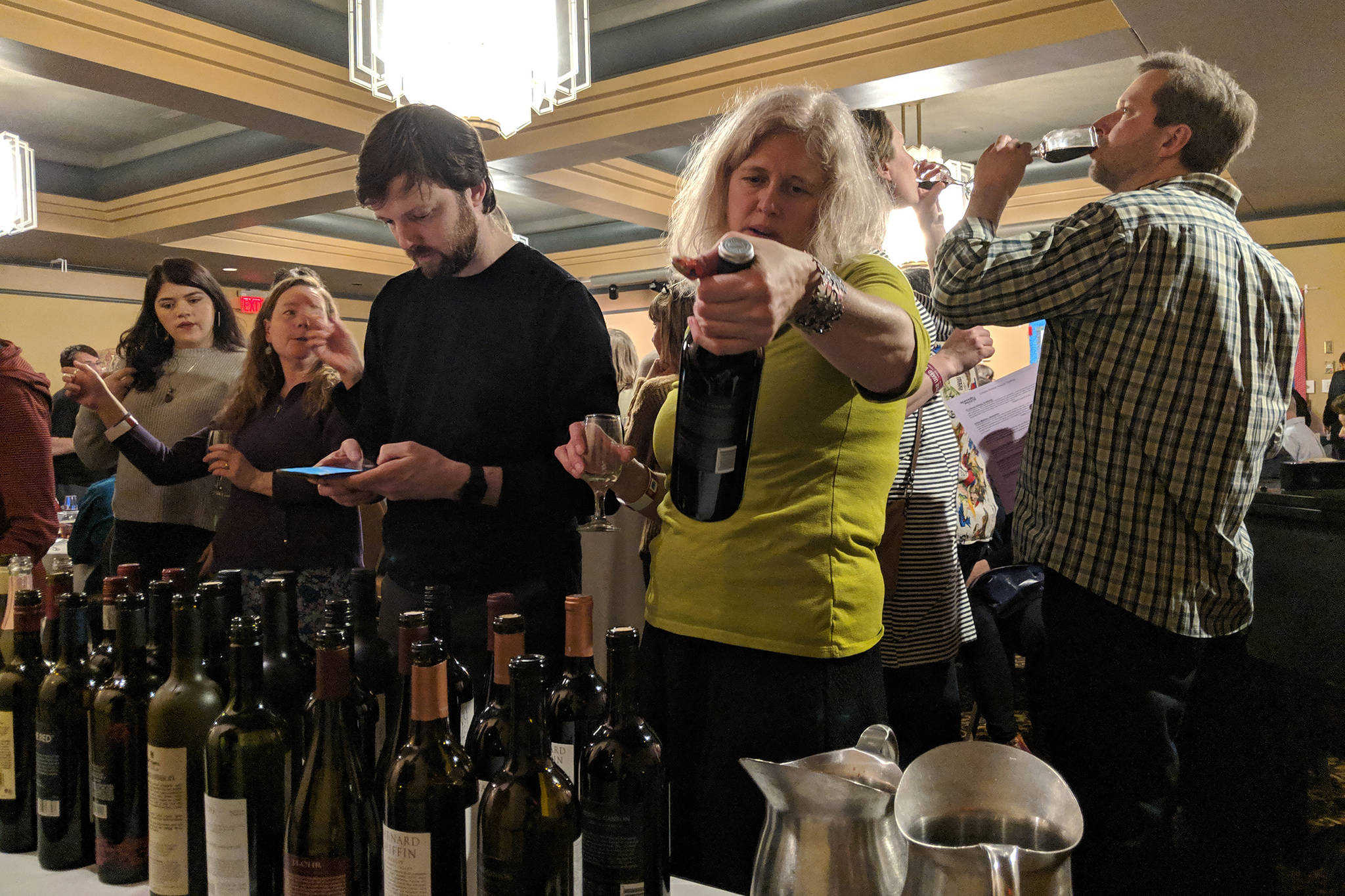 Kirsten Shelton considers a bottle of wine provided by Specialty Imports at a wine and beer tasting and silent auction benefiting Juneau Animal Rescue at the Westmark Baranof Hotel, Saturday, Feb. 9, 2019. (Ben Hohenstatt | Capital City Weekly)