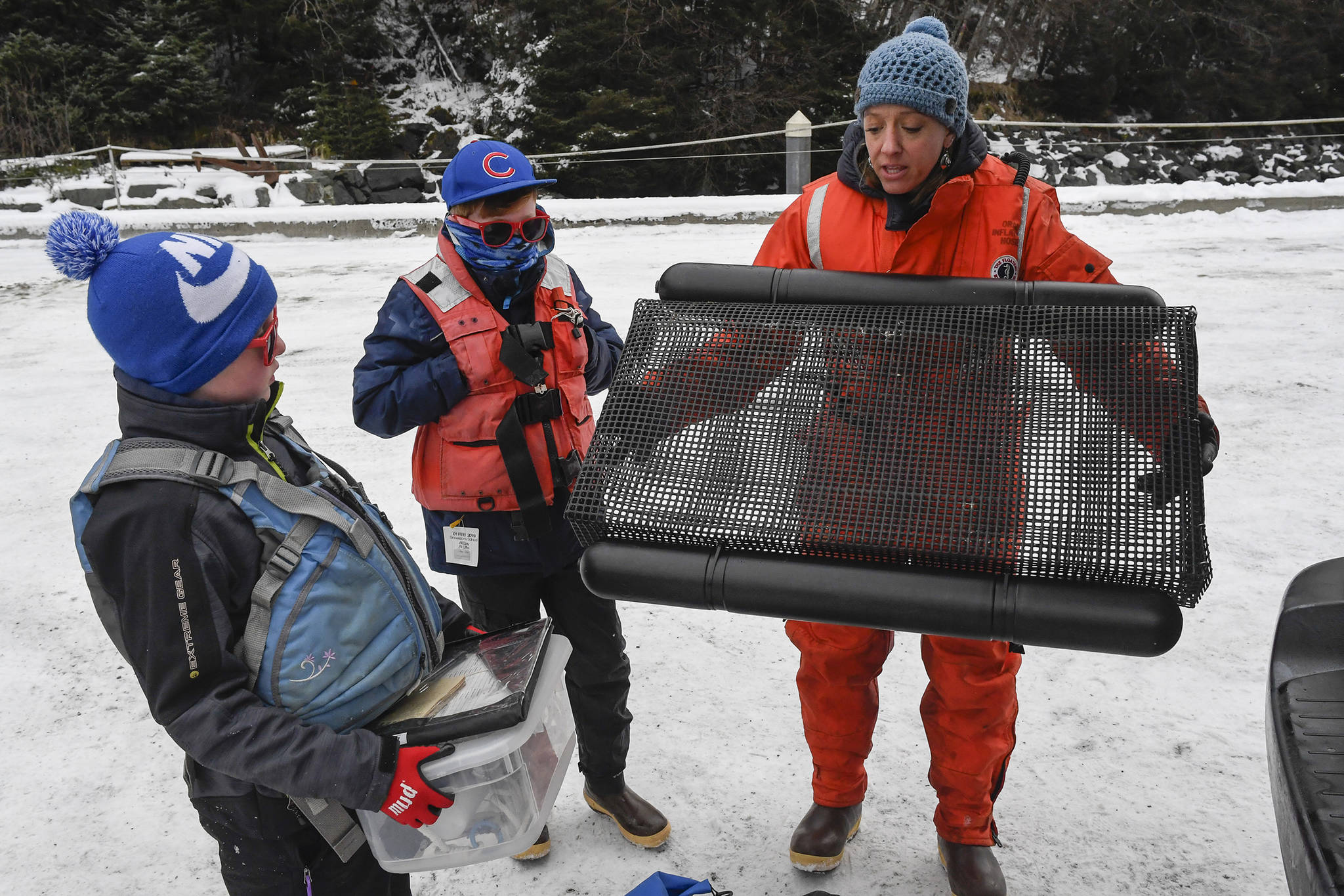 Meta Mesdag, with her sons Kai, 8, left, and Emmett Mesdag, 11, holds a oyster cage used in their Bridget Cove farm on Tuesday, Feb. 12, 2019. (Michael Penn | Juneau Empire)