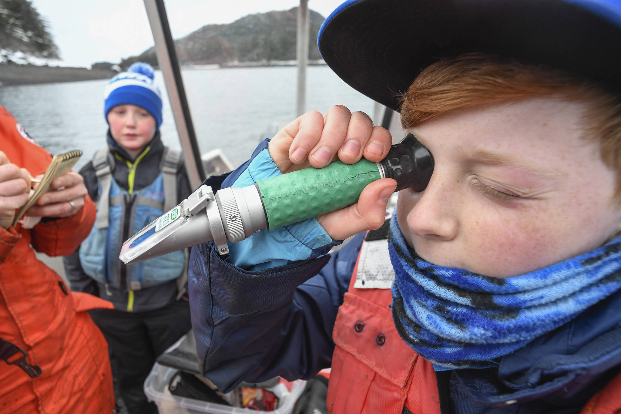 Emmett Mesdag, 11, right, takes a salinity reading while visiting their oyster farm with his mother, Meta Mesdag, and brother, Kai, 8, in Bridget Cove on Tuesday, Feb. 12, 2019. (Michael Penn | Juneau Empire)
