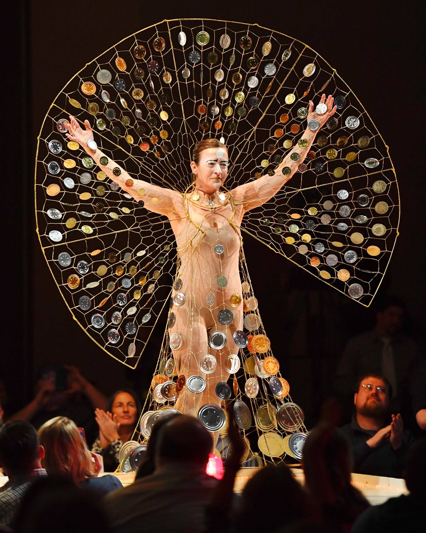 Artist Rhonda Jenkins Gardinier makes her way along the runway in her creation titled “Wishes & Prayers in Turbulent Times” of wire, wire hangers, tin can ends and fishing swivels at the Wearable Art show at Centennial Hall on Saturday, Feb. 16, 2019. (Michael Penn | Capital City Weekly)