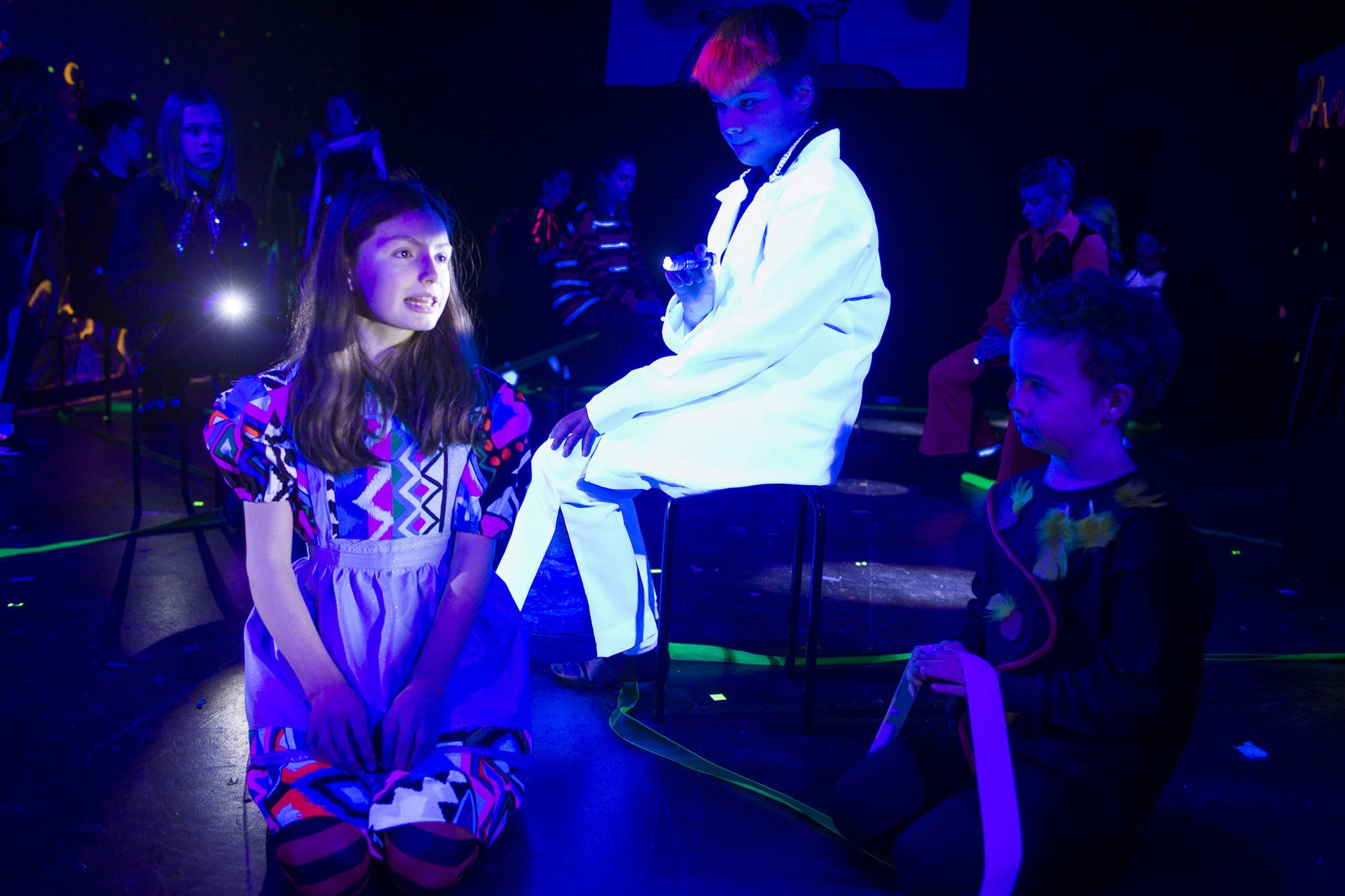 Alice (Sophia Nylen) explores the disorienting Hall of Doors and its resident Wonders (Kyra Wood and Alex Boily, right) in a black-light scene from “DISCO ALICE: The Wonderland Remix” during rehearsal by Perseverance Theatre’s Young Company on Monday, Feb. 25, 2019. (Michael Penn | Juneau Empire)