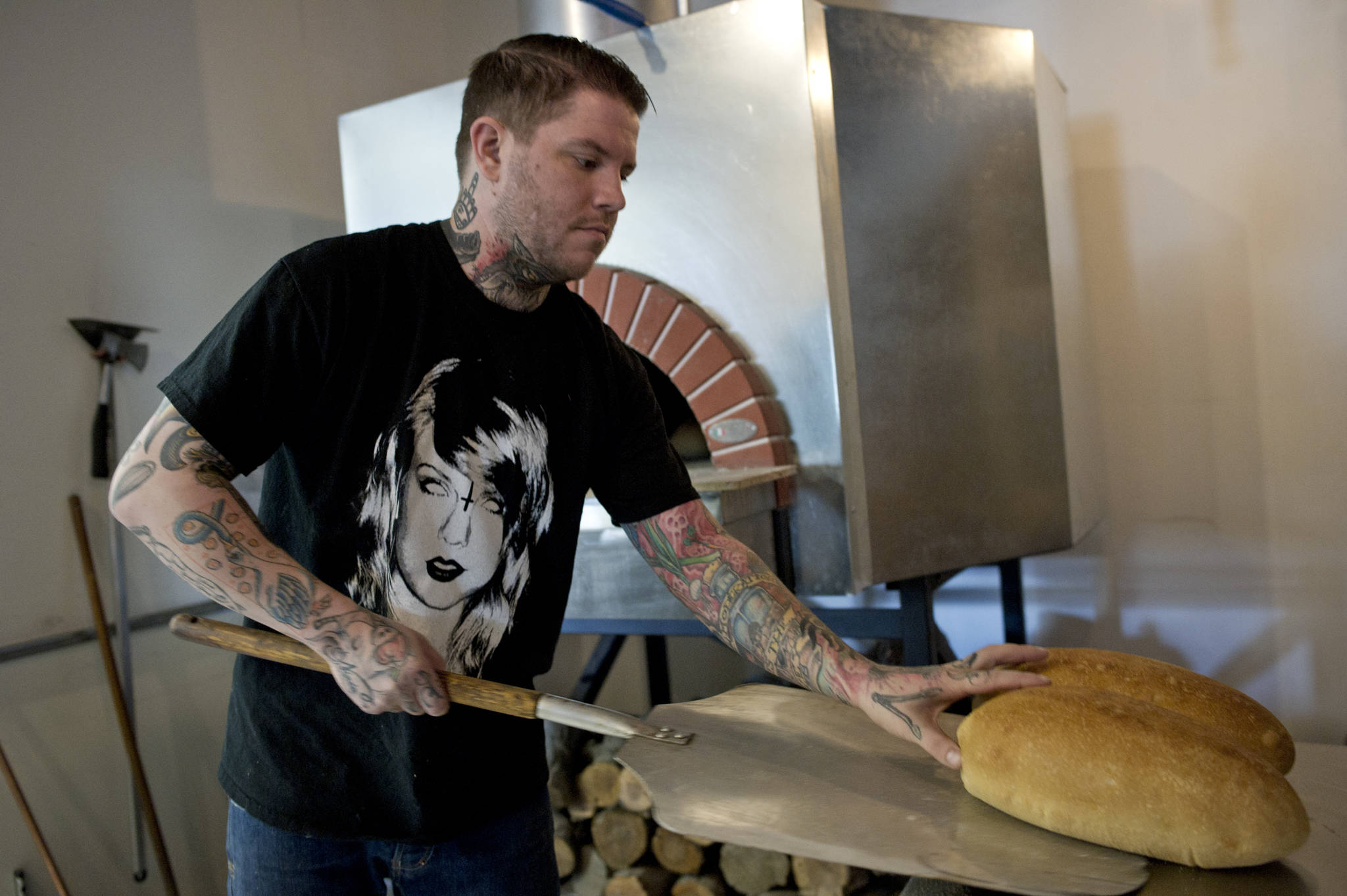 Chef Beau Schooler pulls fresh bread out a wood-fired oven at the new Italian restaurant “In Bocca Al Lupo” downtown in this March 2016 file photo. (Michael Penn | Juneau Empire File)