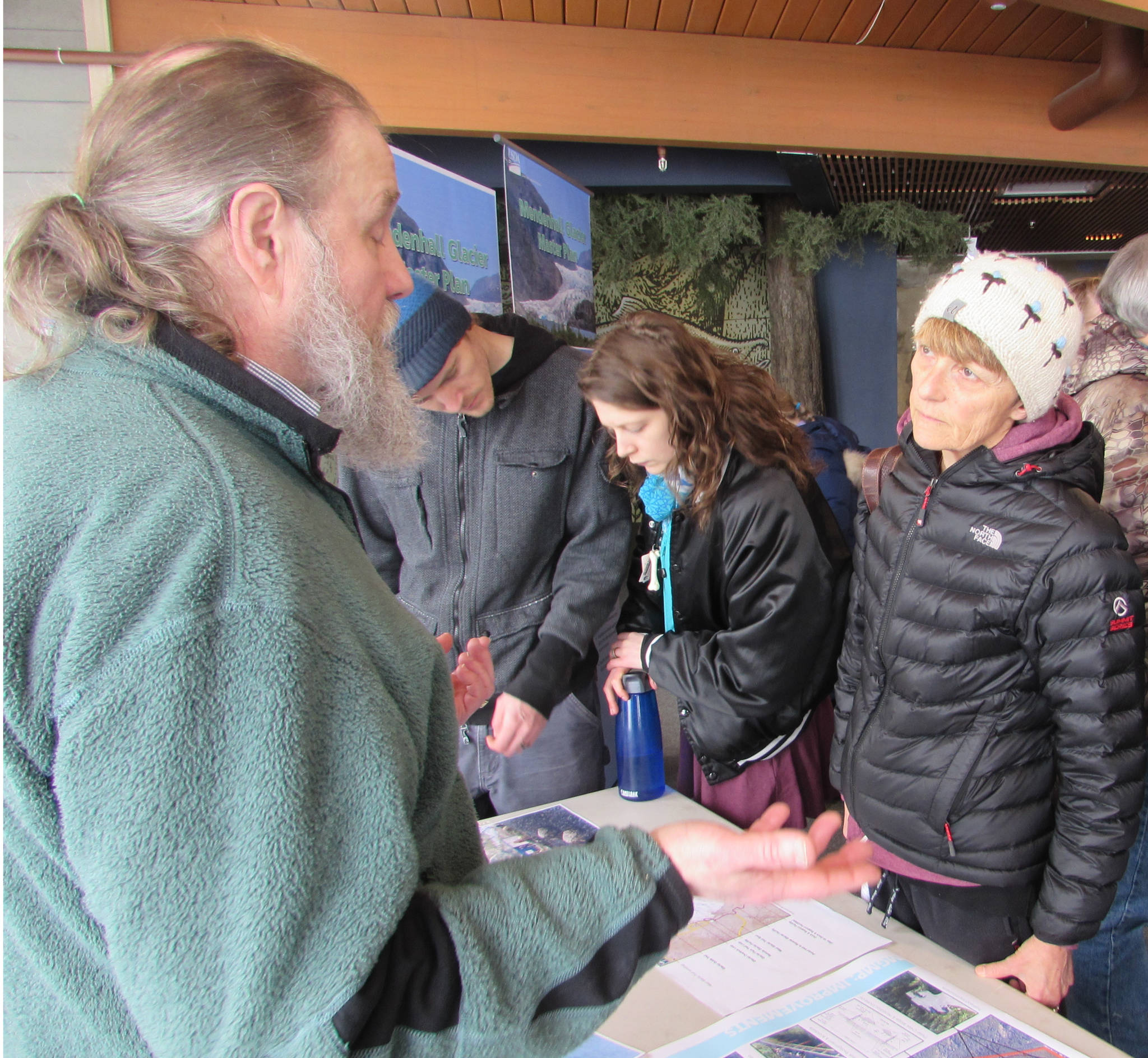 Eric Ouderkirk, left, Alaska Region regional landscape architect for the U.S. Forest Service, talks with Juneau resident Justine Muench, far right, in the Mendenhall Glacier Visitor Center, Saturday, March 2, 2019. (Ben Hohenstatt | Juneau Empire)