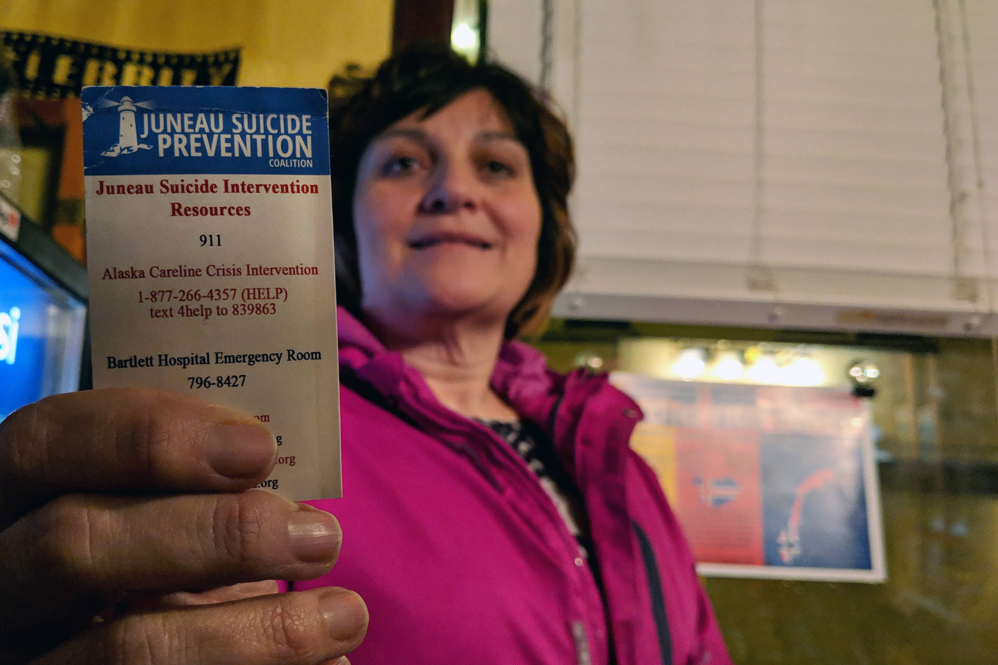 Jan Reece, outreach/training specialist for Juneau Suicide Prevention Coalition, holds up a card with contact information for suicide prevention resources after a screening of “The S-Word” at Gold Town Theater, Tuesday, March 5, 2019. (Ben Hohenstatt | Capital City Weekly)