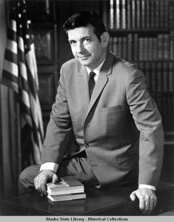 Gov. Keith Miller, sits on the edge of a desk with his hand on two books in his formal portrait. (Courtesy Photo | Alaska State Library Historical Collections, ASL-Miller-Keith-01)