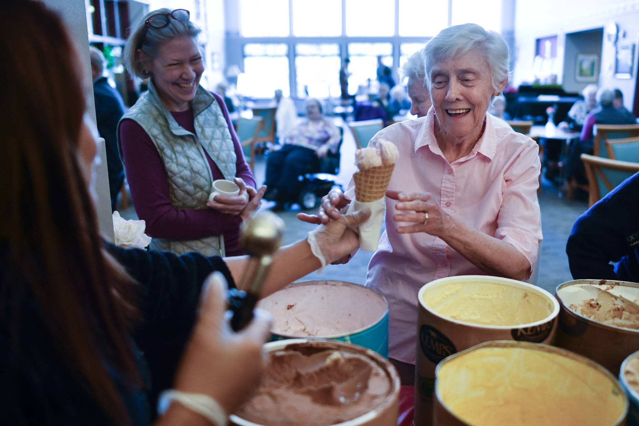 Alaska Pioneer Home resident Phyllis Woodman, right, receives a cone of ice cream from employee Myra Kalbaugh during the homes weekly ice cream social on Friday, March 8, 2019. (Michael Penn | Juneau Empire)