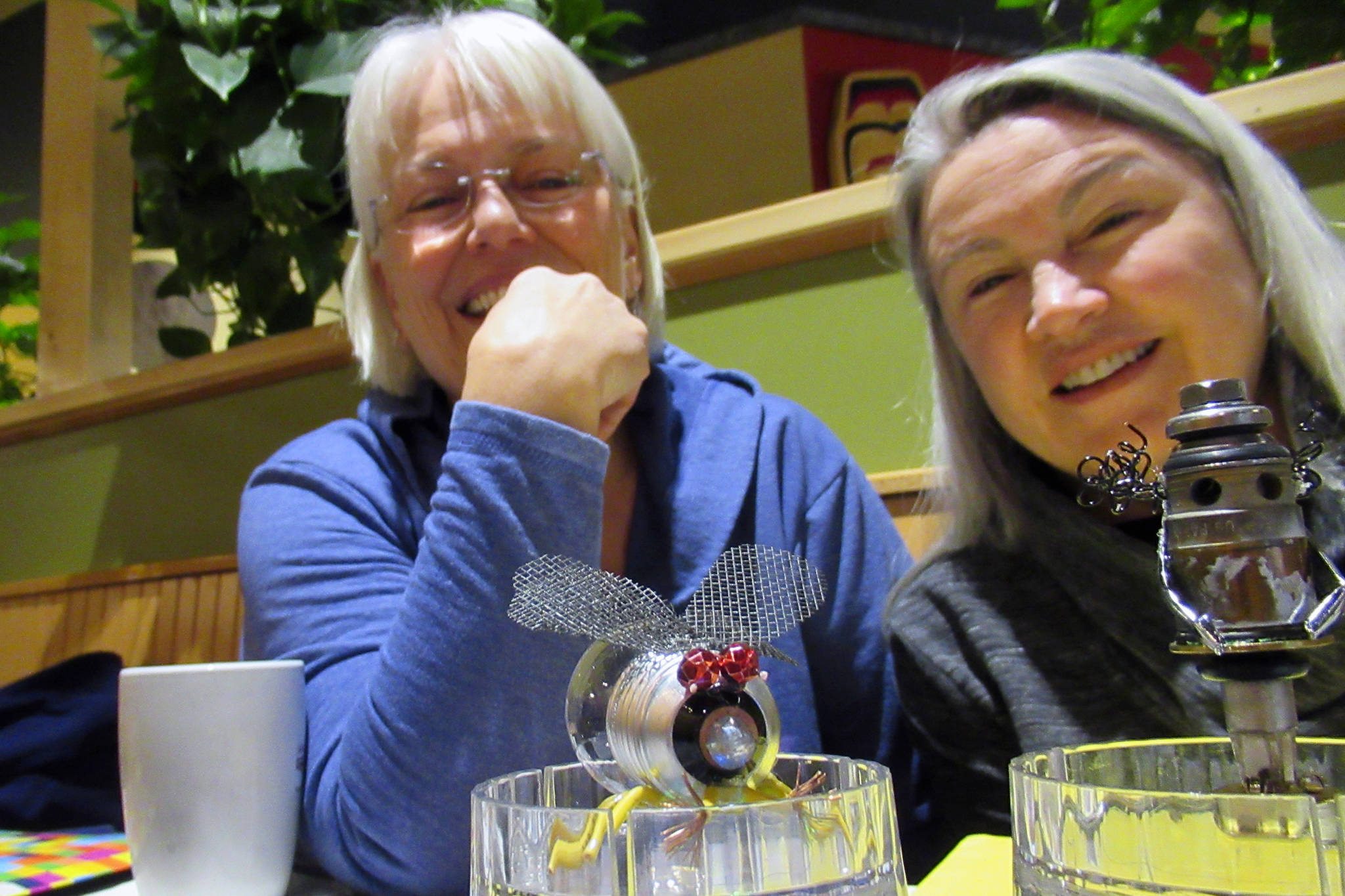 Rotarians Candy Behrends and Diane Kyser smile while talking about a planned assemblage art show and building contest near pieces of art made from household items, Tuesday, March 12, 2019. (Ben Hohenstatt | Juneau Empire)