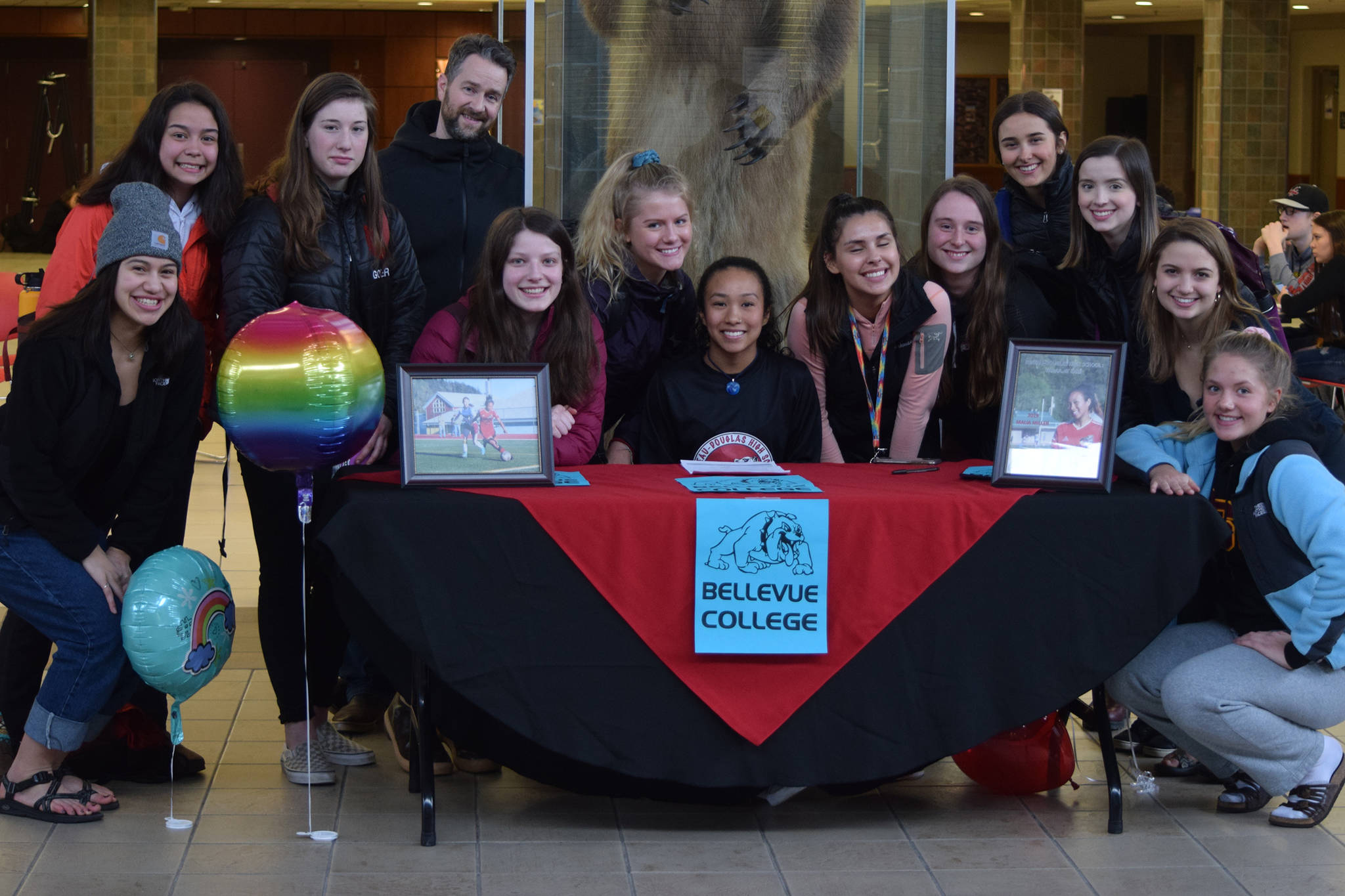 Juneau-Douglas High School senior Malia Miller (seated) poses with her teammates on the JDHS soccer team after signing a National Letter of Intent with Bellevue College at the JDHS commons on Thursday, March 14, 2019. (Nolin Ainsworth | Juneau Empire)