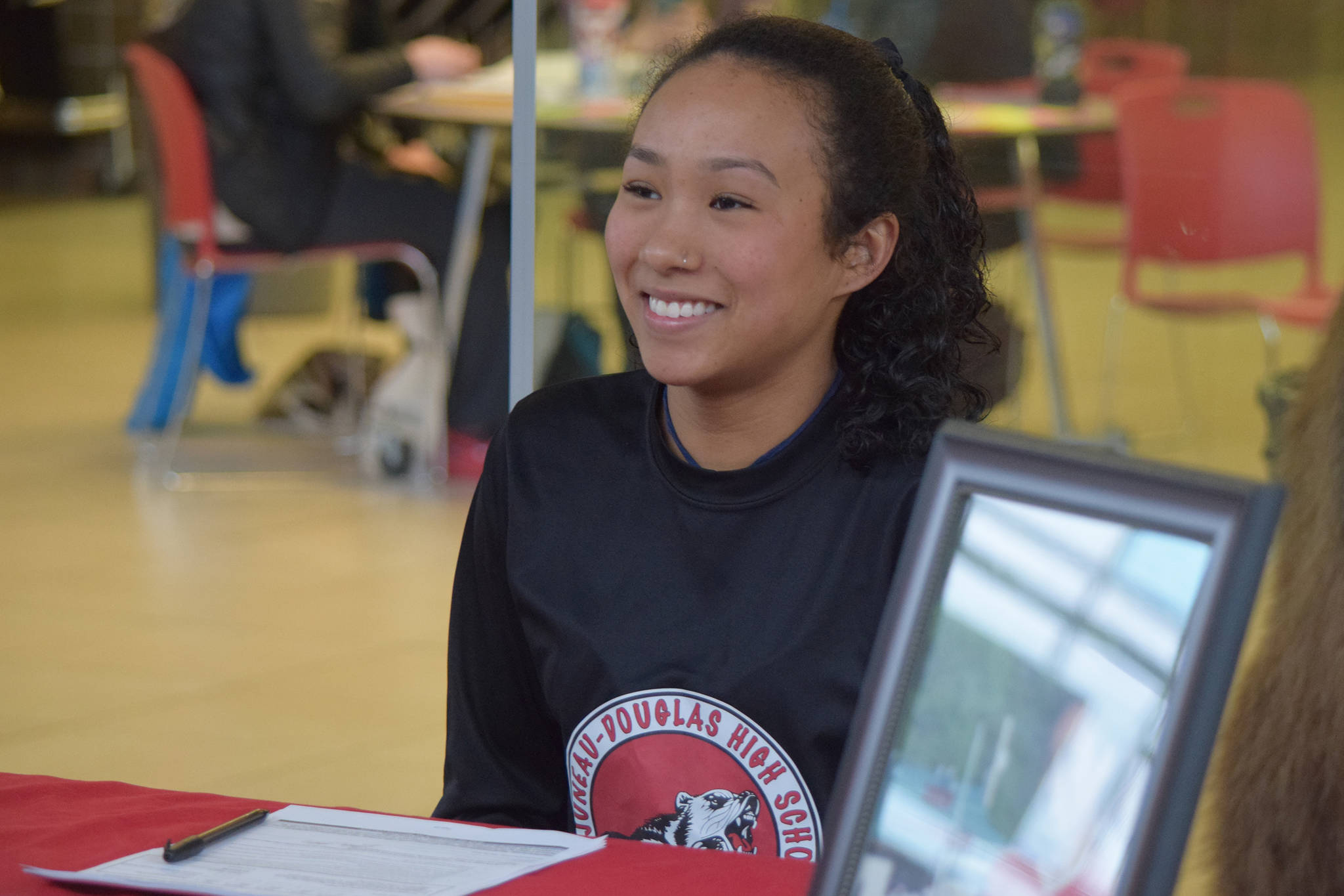 Juneau-Douglas High School senior Malia Miller finishes signing a National Letter of Intent with Bellevue College at the JDHS commons on Thursday, March 14, 2019. (Nolin Ainsworth | Juneau Empire)