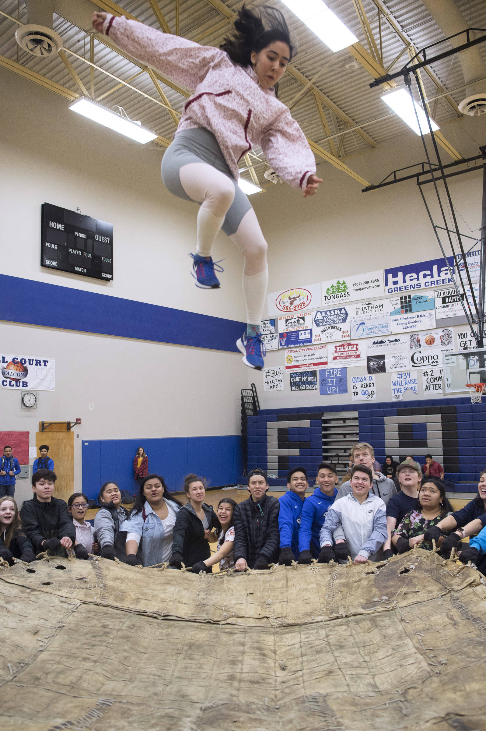 Native Youth Olympics athlete Sara Steeves, a senior at Thunder Mountain High School, takes to the air in a blanket toss demonstration during the lunch hour in the Thunder Mountain High School gymnasium on Friday, March 15, 2019. (Michael Penn | Juneau Empire)