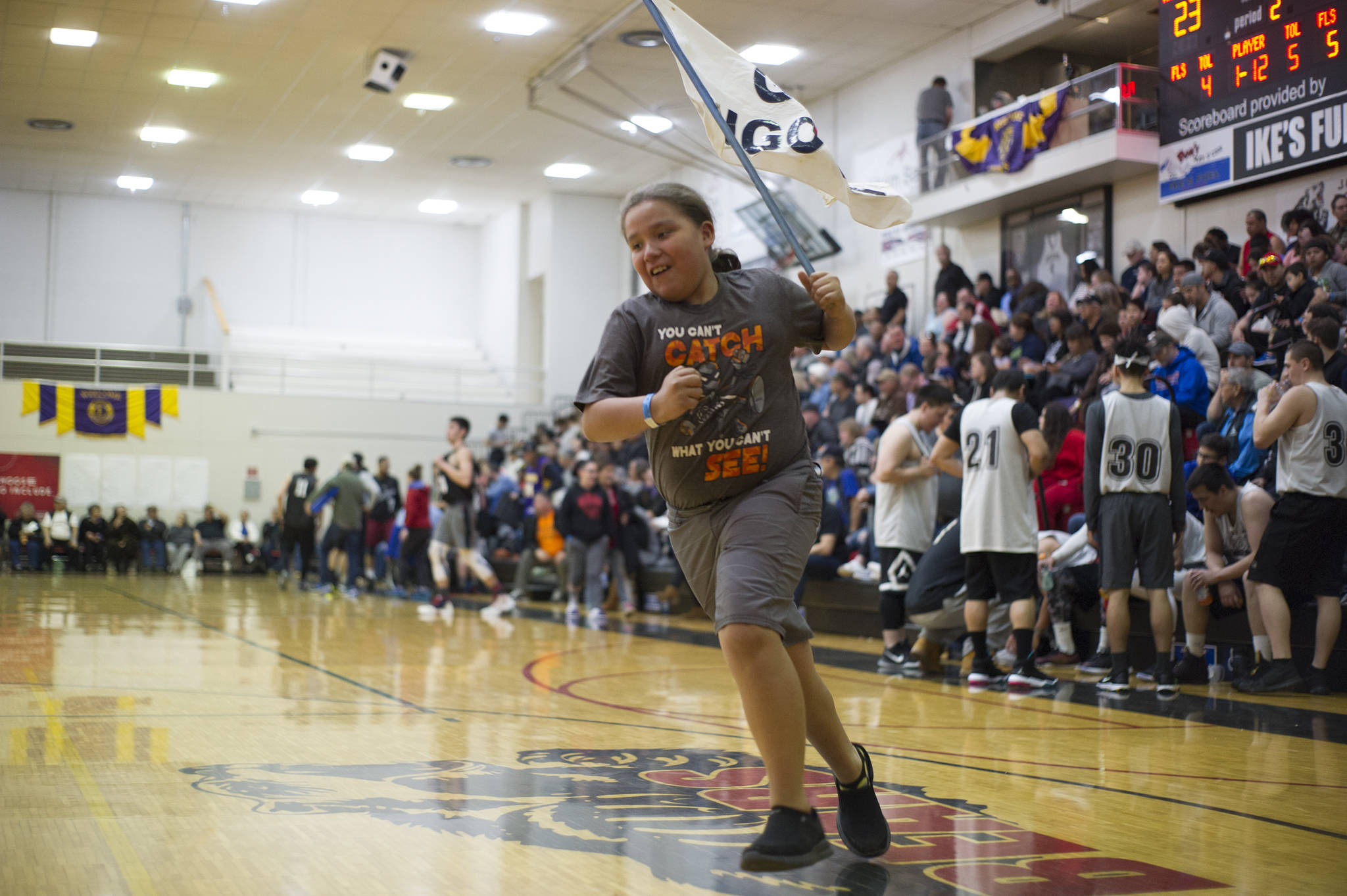 A young fan runs with runs with a Angoon flag in between the first and second quarters of Angoon’s B Bracket game against Metlakatla. (Nolin Ainsworth | Juneau Empire)