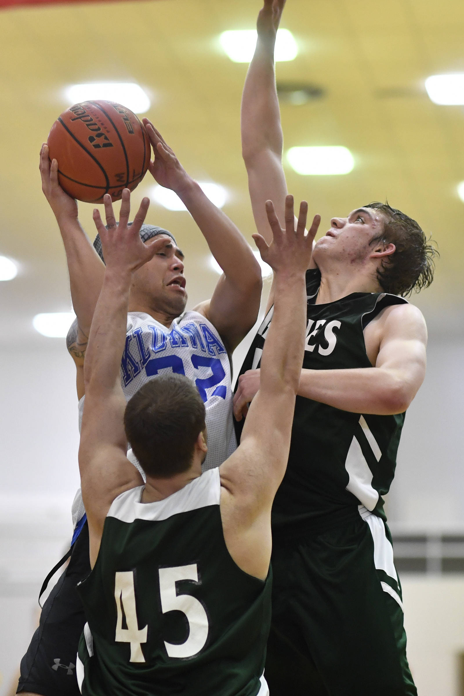 Klukwan’s Terrance Wheat is blocked from shooting by Haines’ Dylon Swinton, right, and Brian Combs in a B bracket game at the Juneau Lions Club 73rd Annual Gold Medal Basketball Tournament at Juneau-Douglas High School: Yadaa.at Kalé on Tuesday, March 19, 2019. Haines won 97-51. (Michael Penn | Juneau Empire)